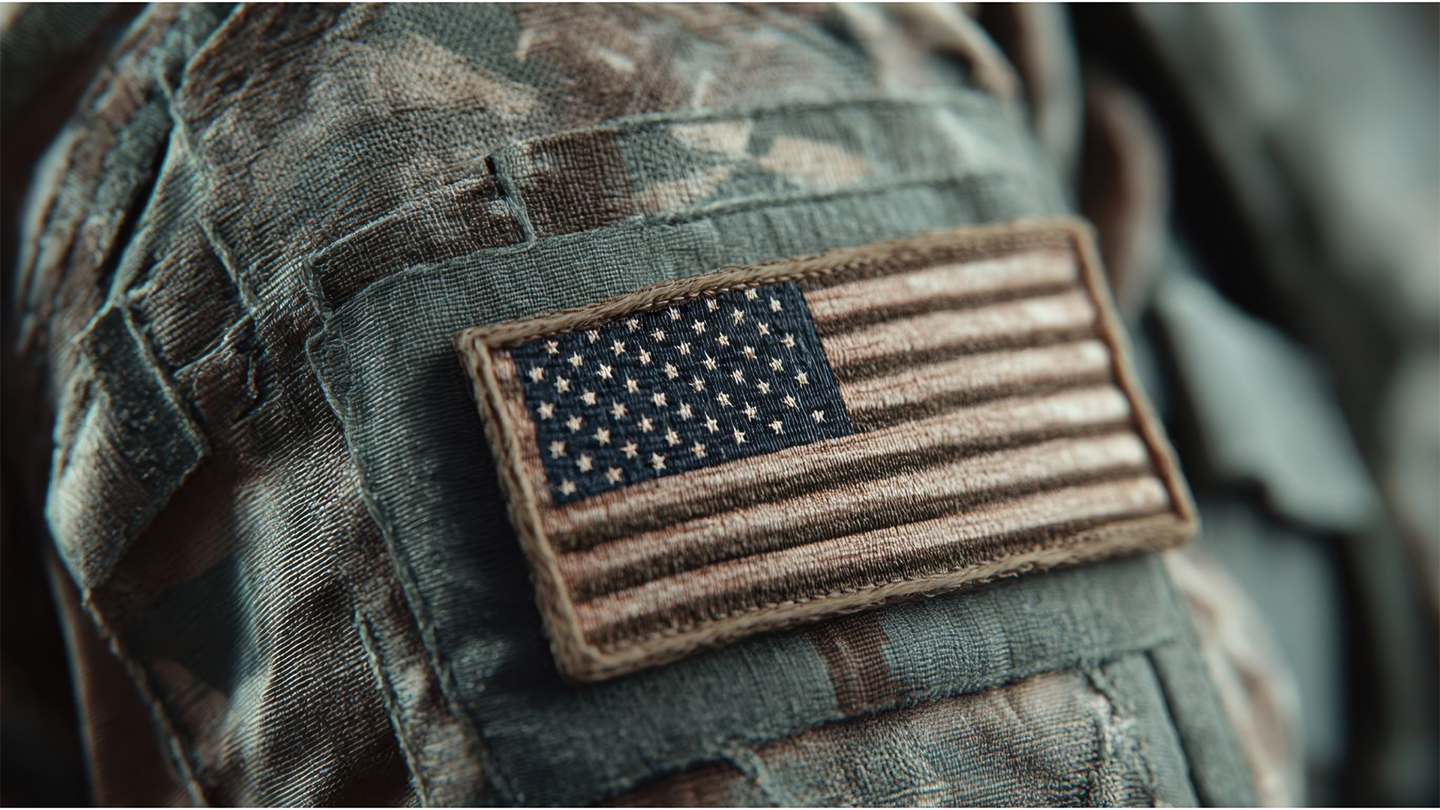 Close-up of a camouflage military uniform with a patch of the American flag.