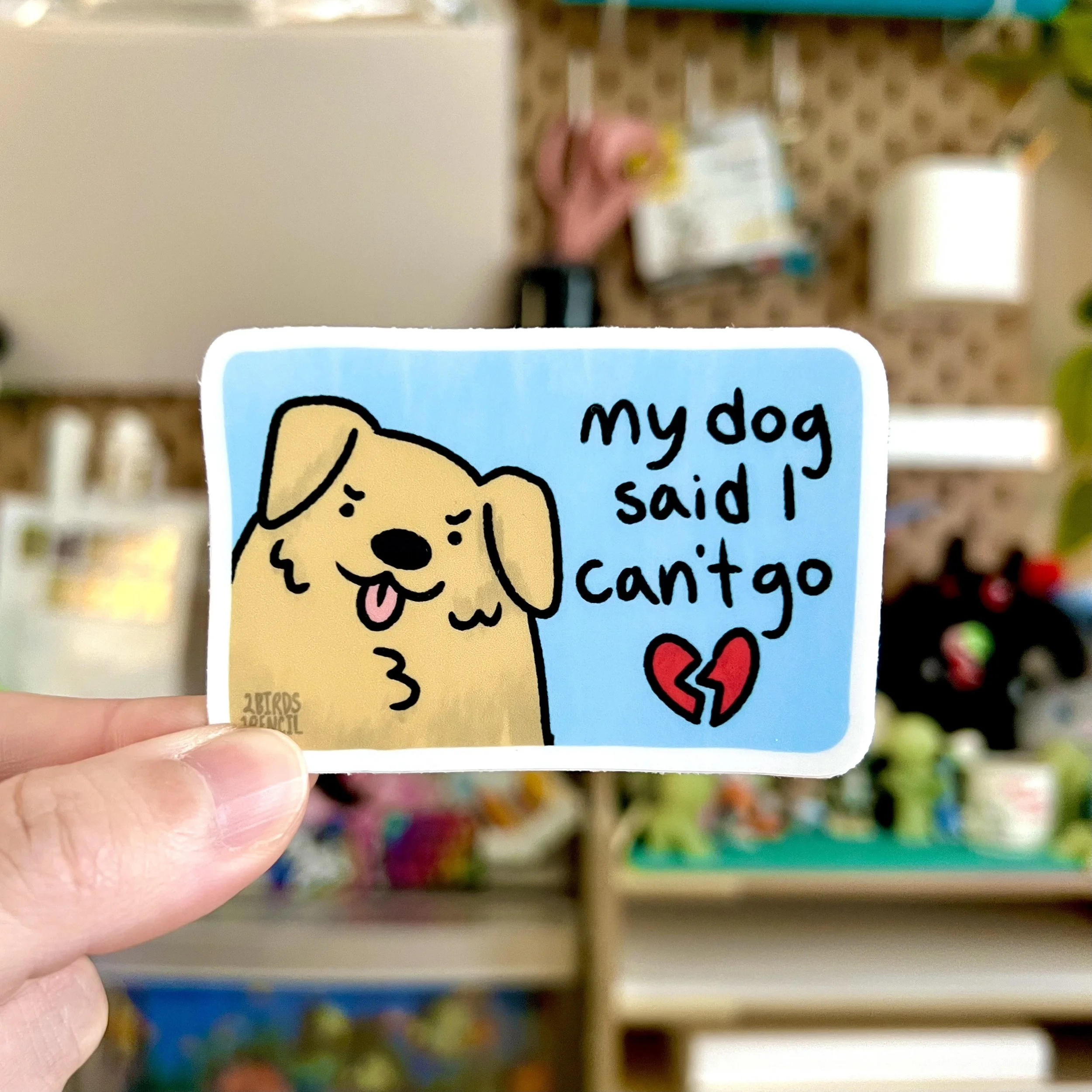 A photo of a vinyl sticker, with an illustration of cartoon dog face looking mischievous. Text next to them reads, "my dog said I can't go" with a broken heart underneath it.
