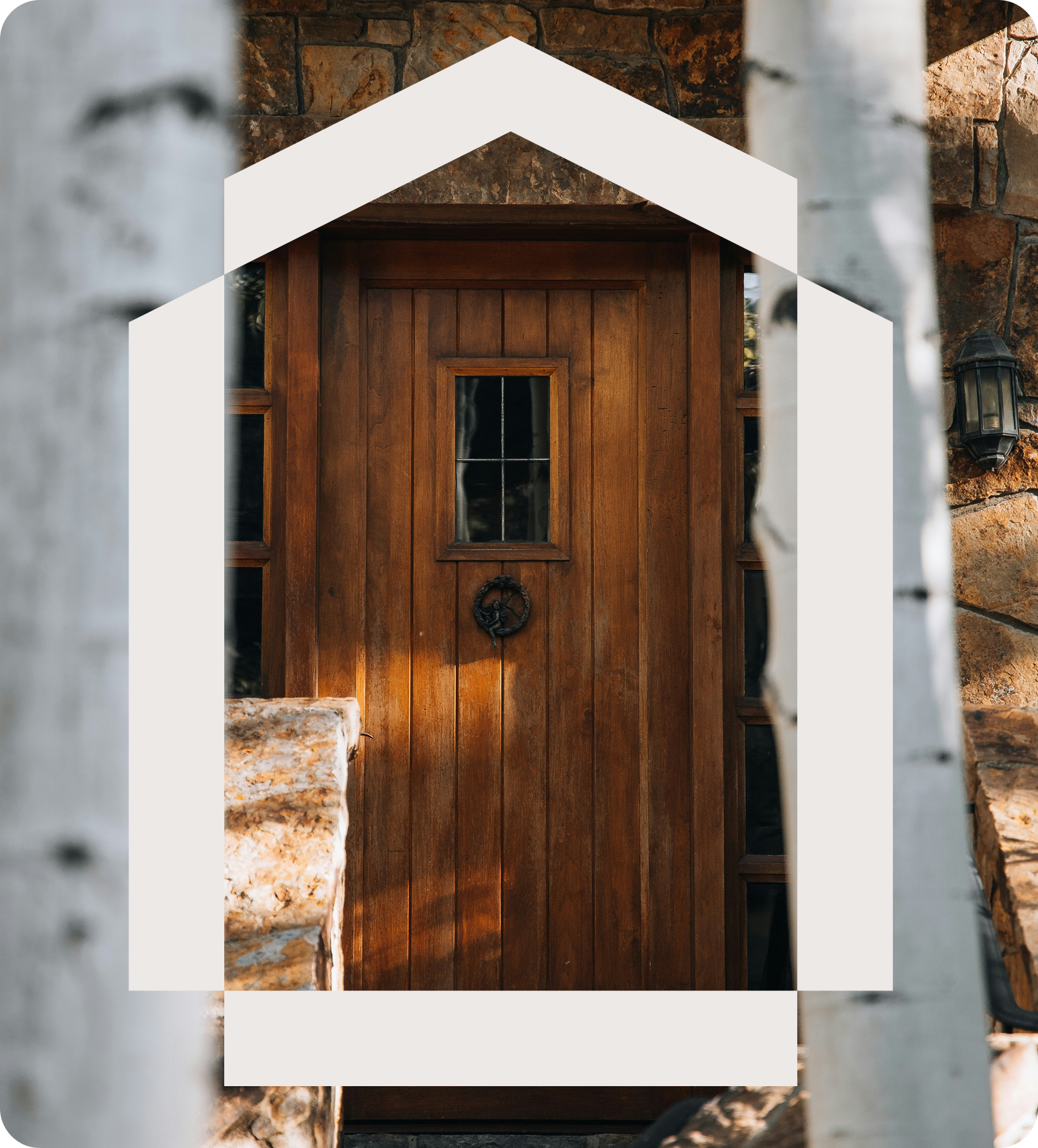 A wooden front door with a small window, surrounded by a stone wall, viewed through white metal bars.