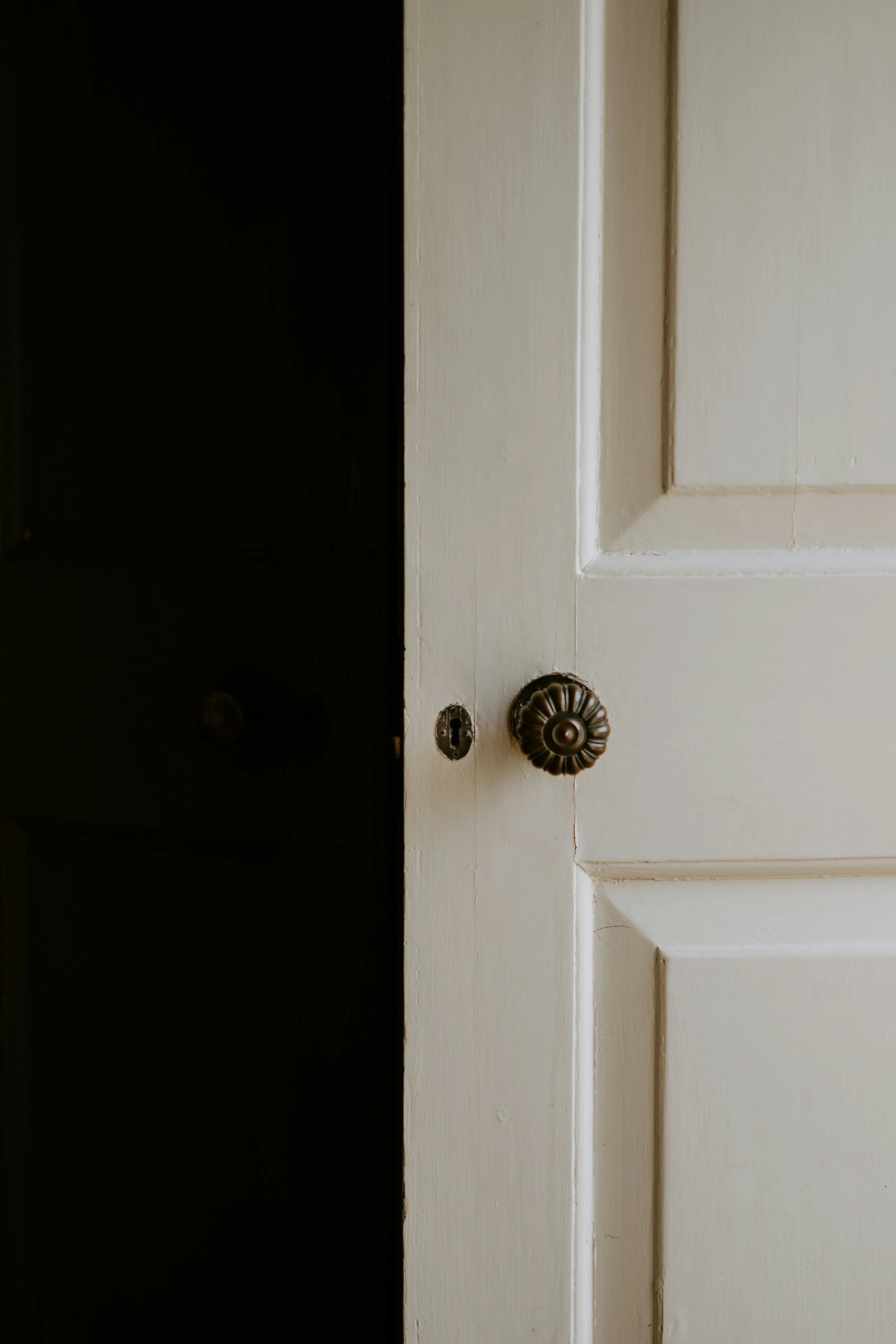 Close-up of a white wooden door with a decorative doorknob and a keyhole on the left side.
