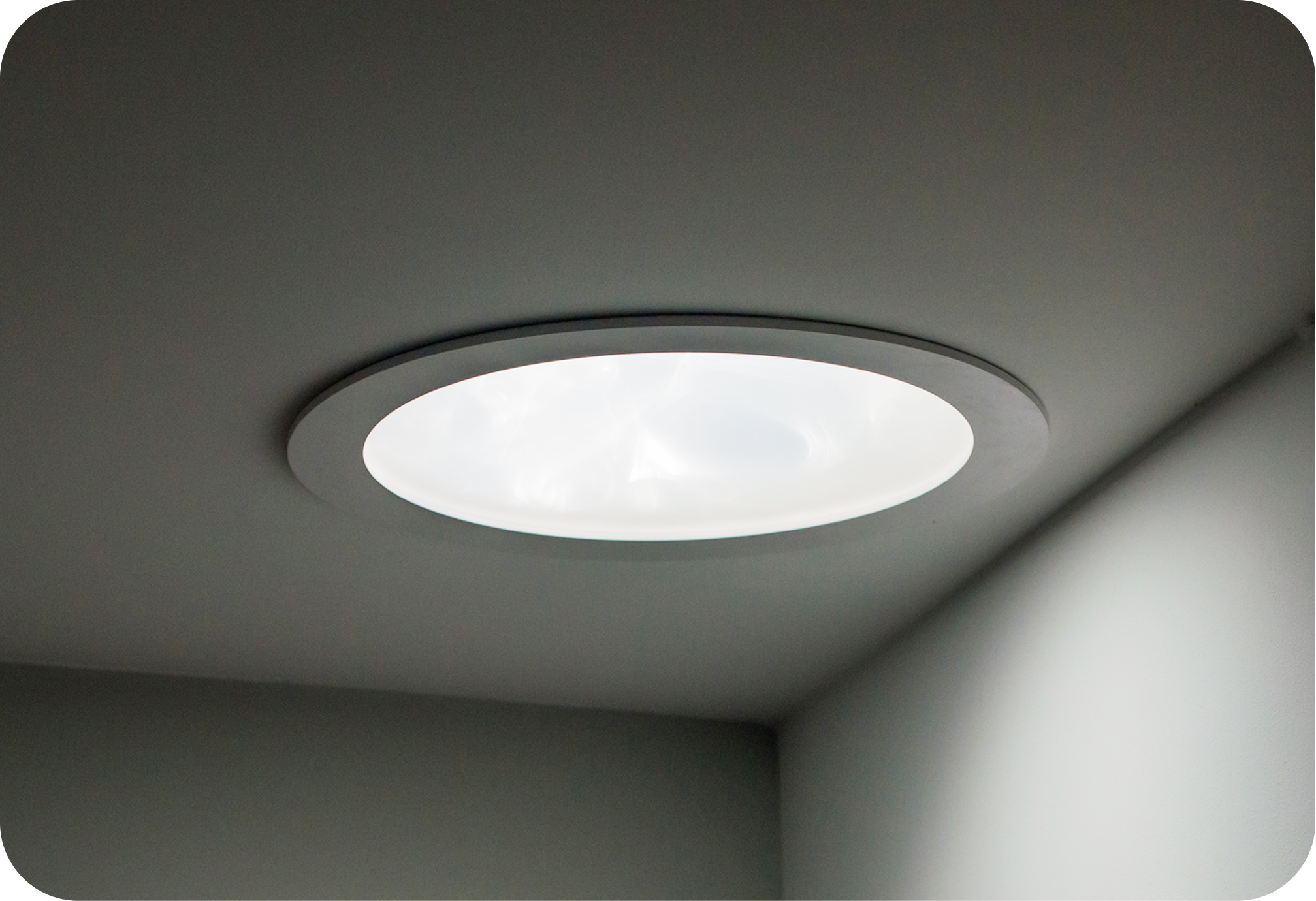 Ceiling light fixture with a circular white cover in a ceiling.