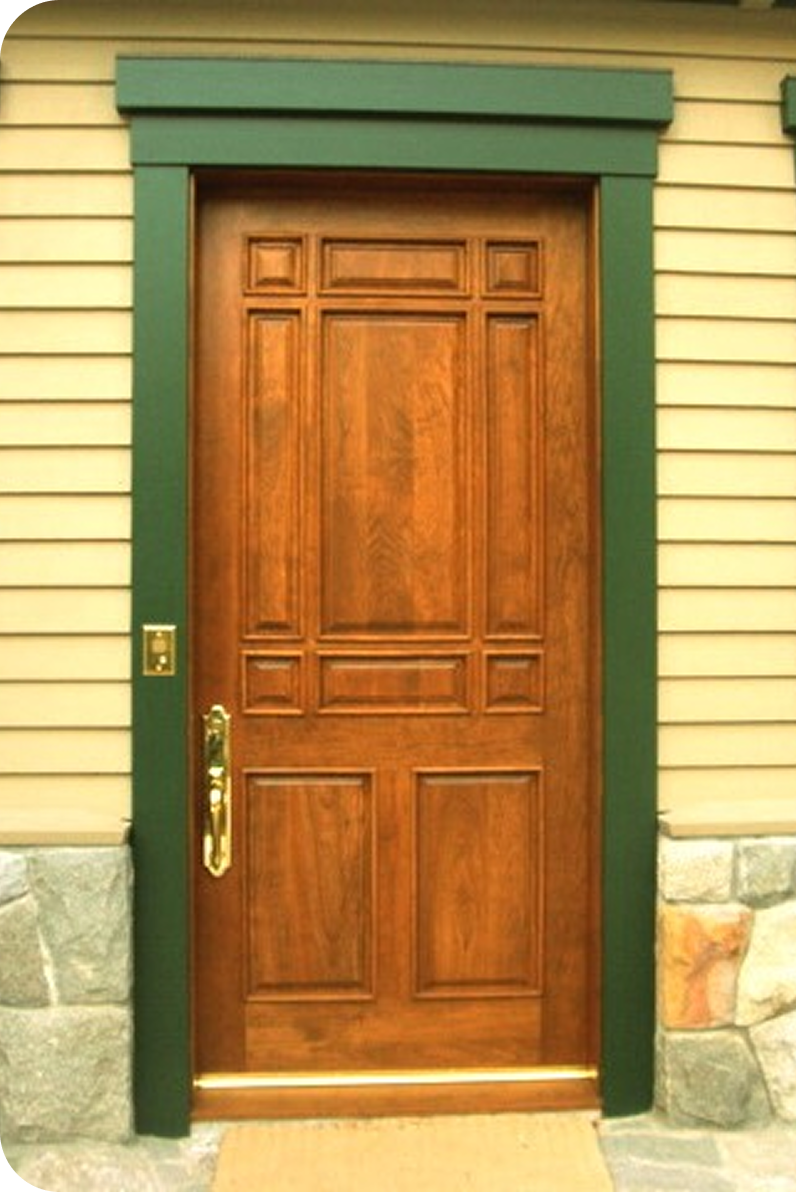 Front view of a wooden door with green trim and stone base, tied into a siding house.