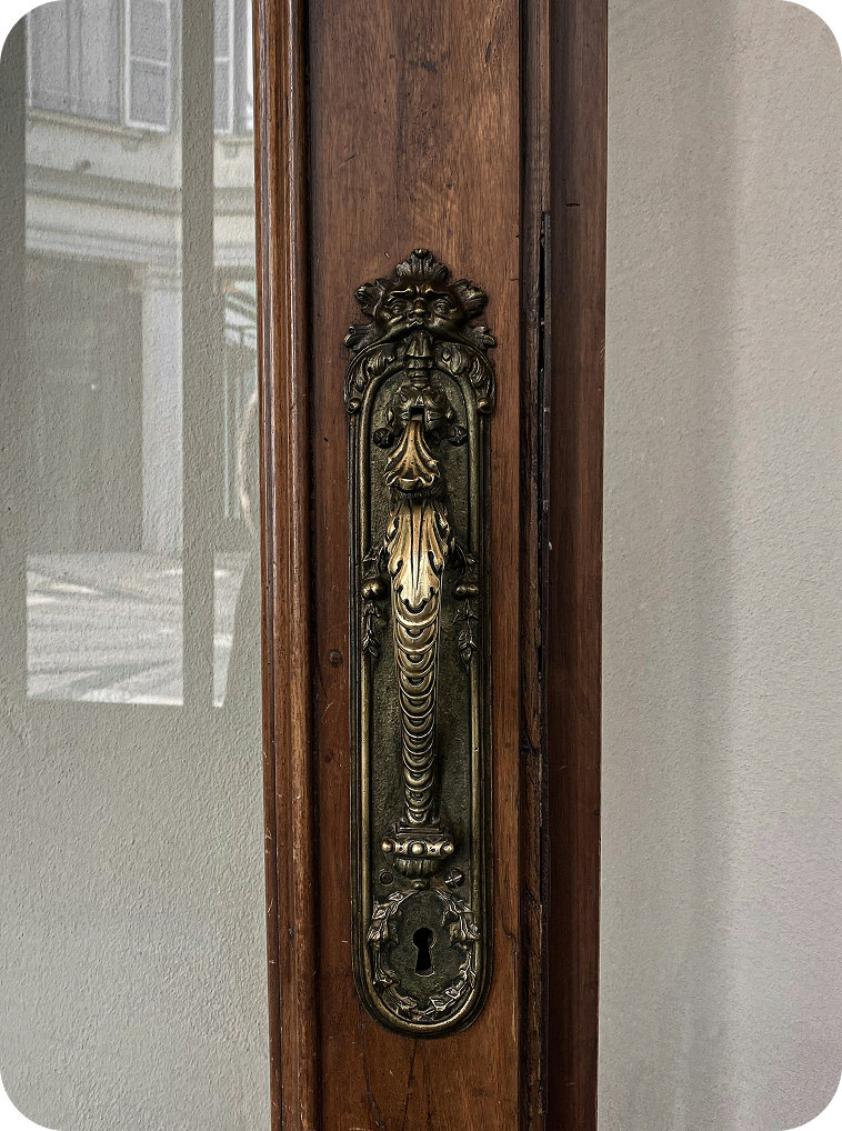 Close-up of a vintage brass door handle and keyhole on a wooden door.
