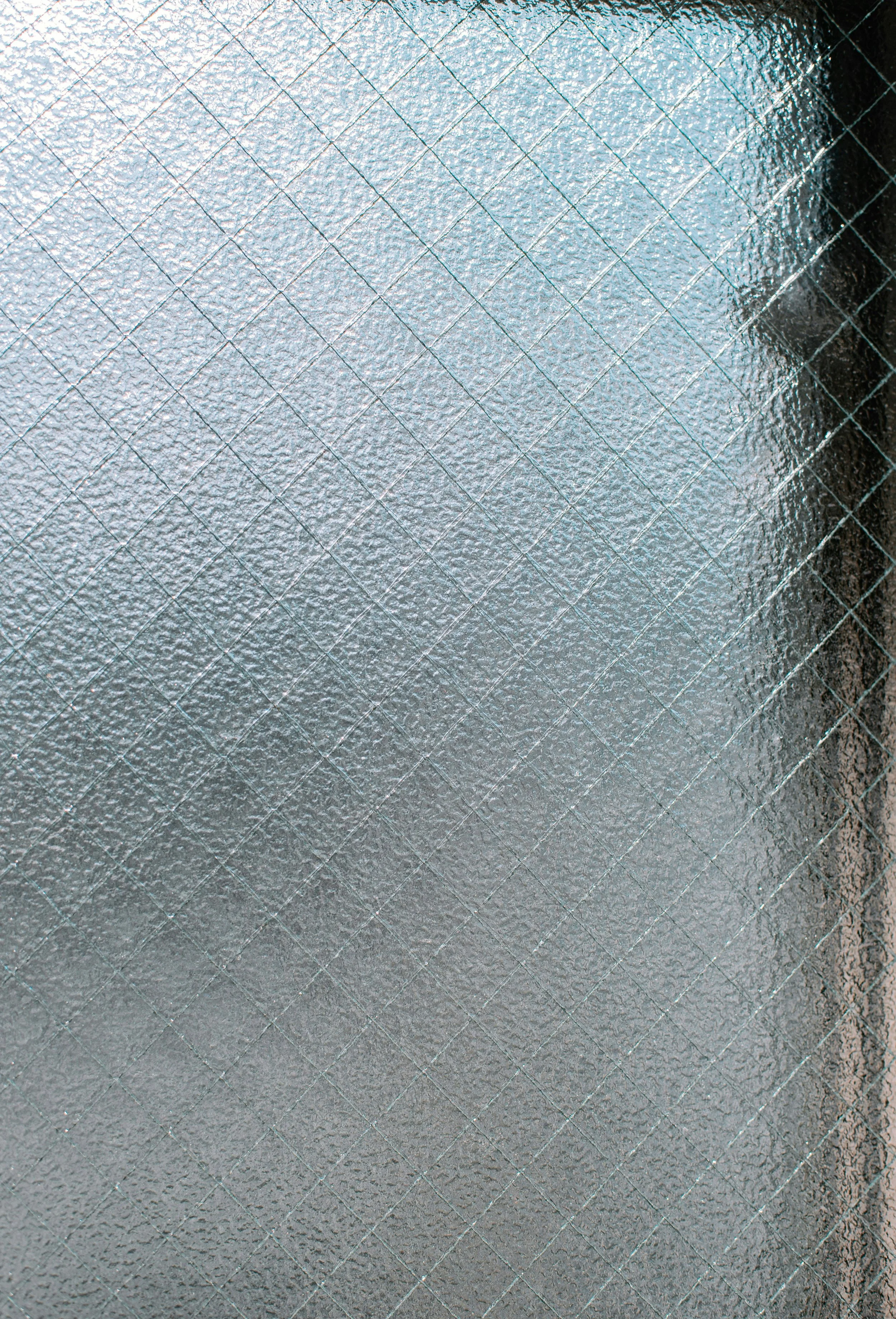 Close-up of a textured aluminum surface with a diamond-patterned grid of embossed lines.