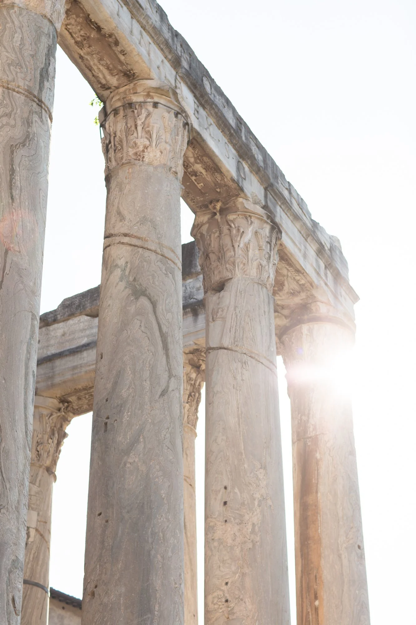 Close-up of ancient stone columns with intricate carvings, sunlight shining through gaps at the top.