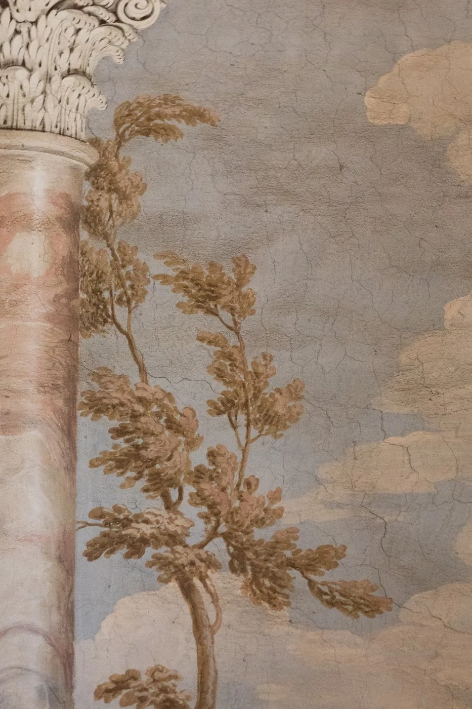 Fresco painting of a cloudy sky with a tree, featuring a decorative column on the left.