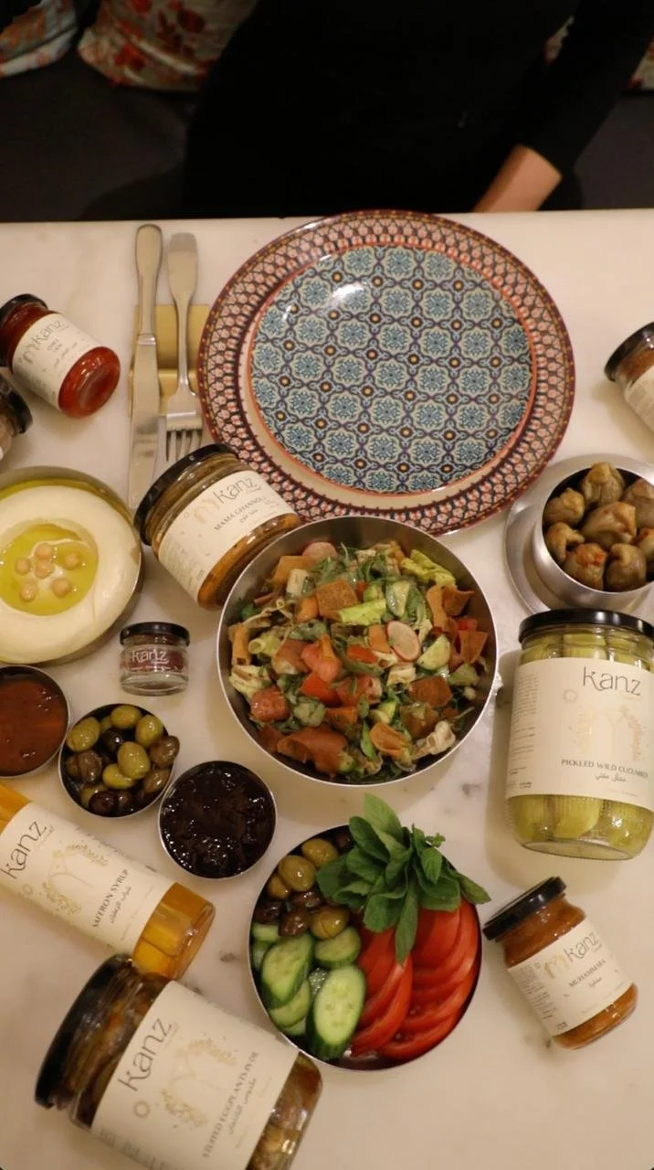 A Mediterranean-style meal with various dips, salad, pickles, and condiments on a table.