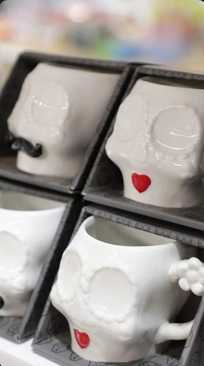 Close-up of skull-shaped ceramic cups with heart details in store packaging.