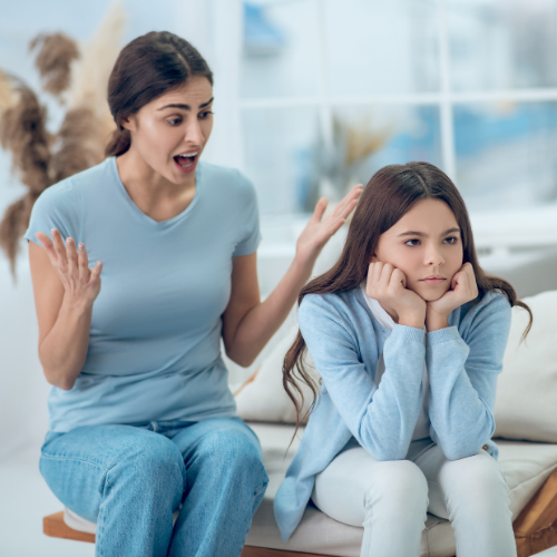Una donna arrabbiata discute con una ragazza triste e annoiata seduta sul divano.