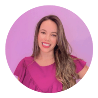 Una donna con capelli lunghi e castani che sorride, indossa una maglietta rosa con sfondo viola