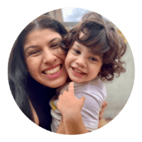 Una donna sorridente che tiene in braccio una giovane bambina che sorride. Sembrano felici.