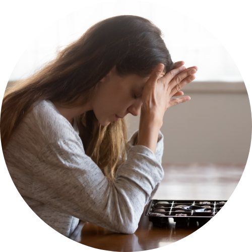 Una donna con espressione preoccupata seduta al tavolo con un cassetto chiuso davanti a lei.