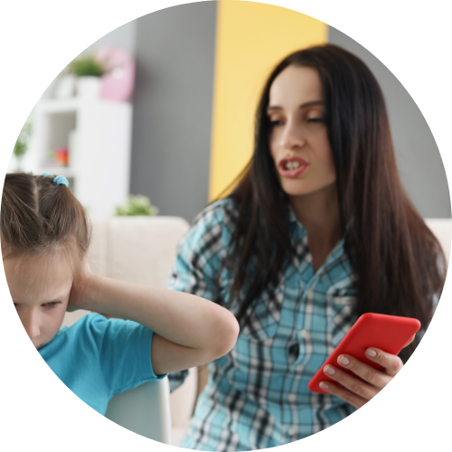 Una donna con abbigliamento a scacchi che tiene in mano uno smartphone, mentre una bambina con maglietta blu si guarda le orecchie in una stanza domestica.