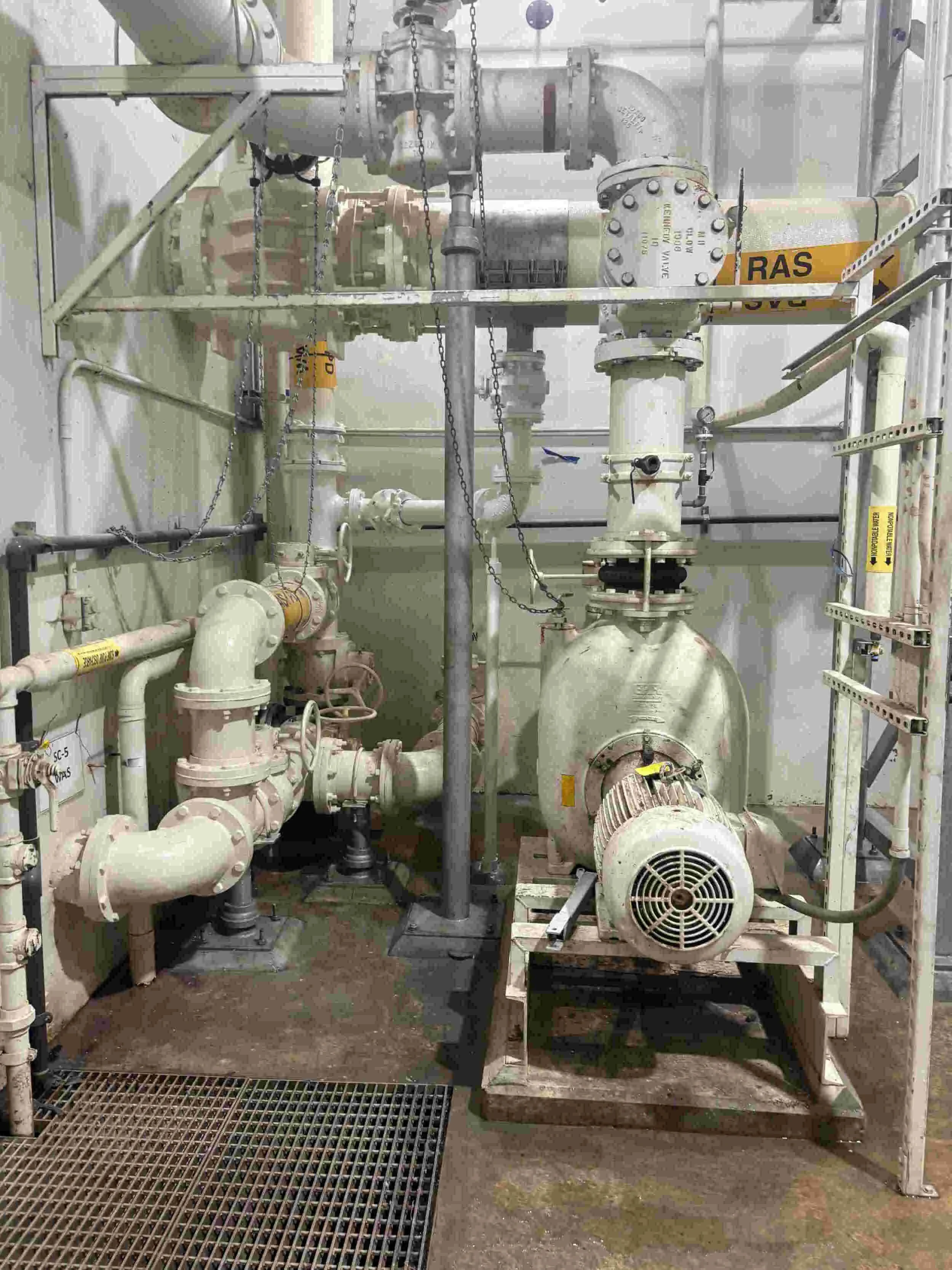 Industrial pumps and pipes with labels and safety markings in a processing plant.