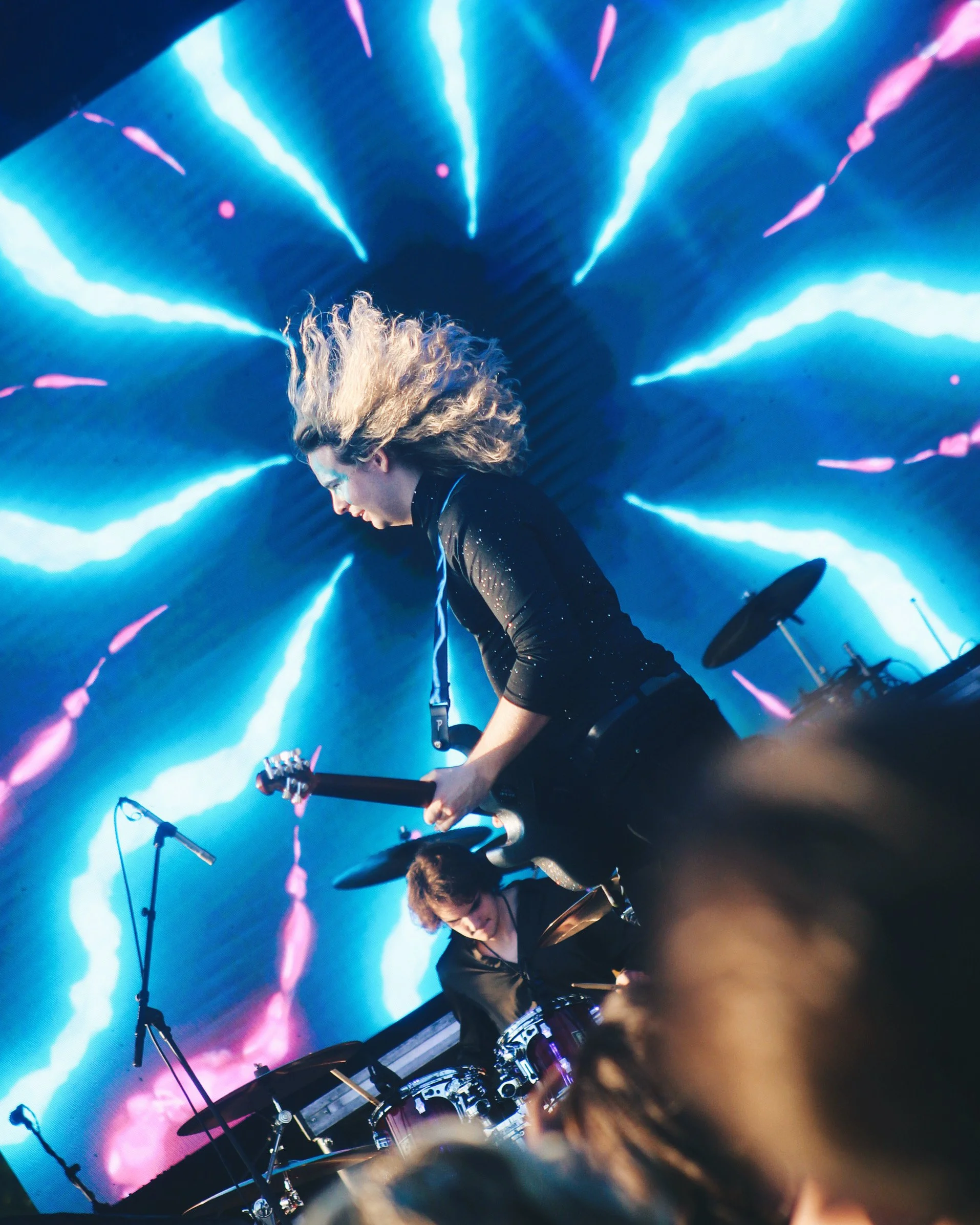 Musicians performing on stage with a vibrant, neon lightning background.