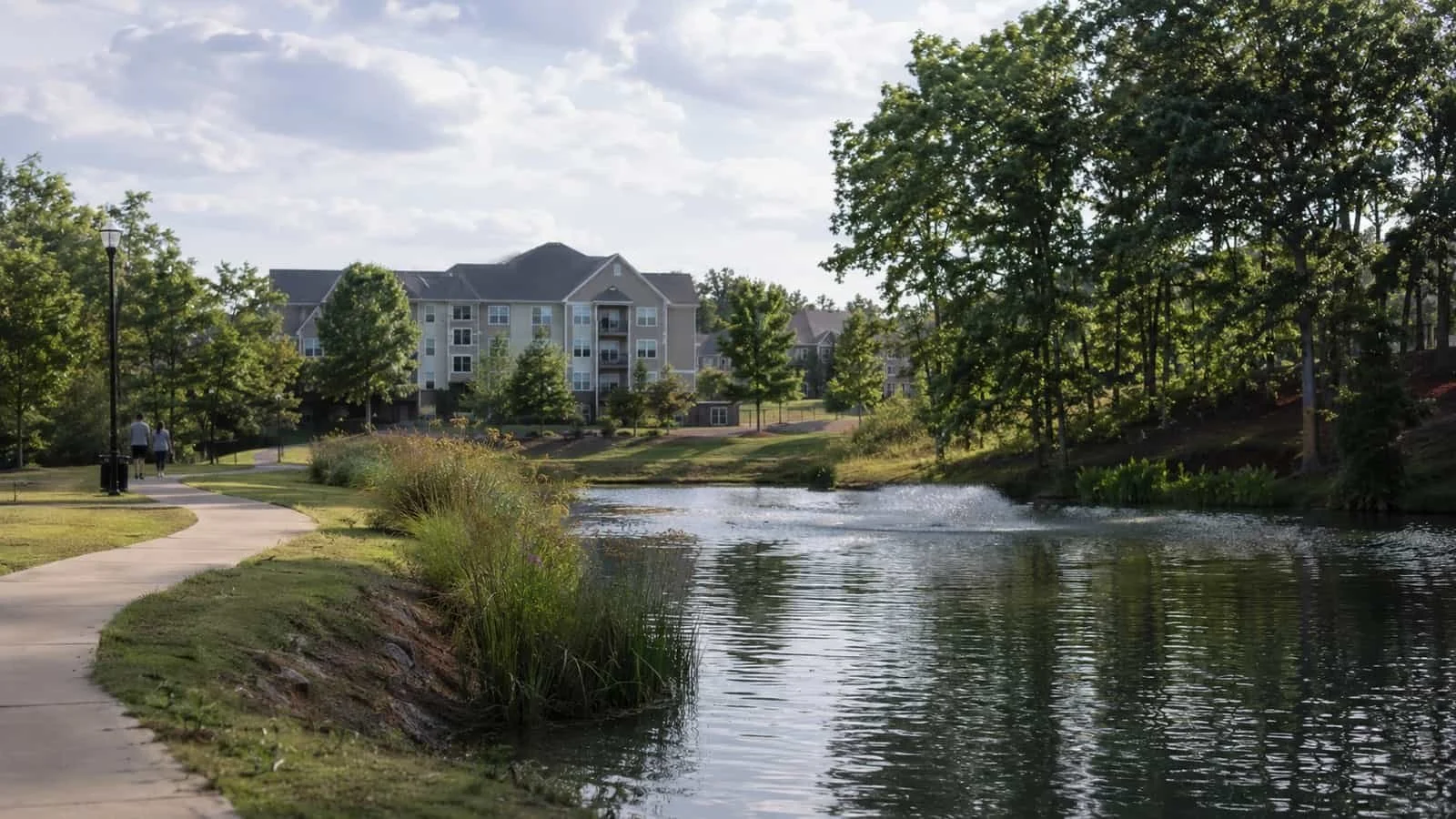 Residents enjoying a clean, clear pond and dry walkways at a modern NC apartment community.