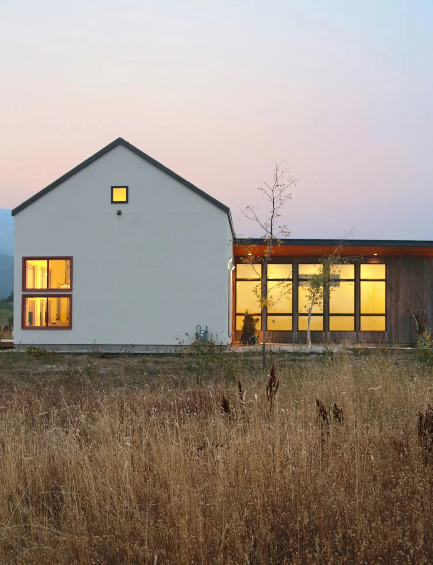 Scandinavian inspired home with old-world stucco plaster exterior walls and large modern aluminum windows. Warm rustic cedar wood siding is juxtaposed against the clean modern white stucco.