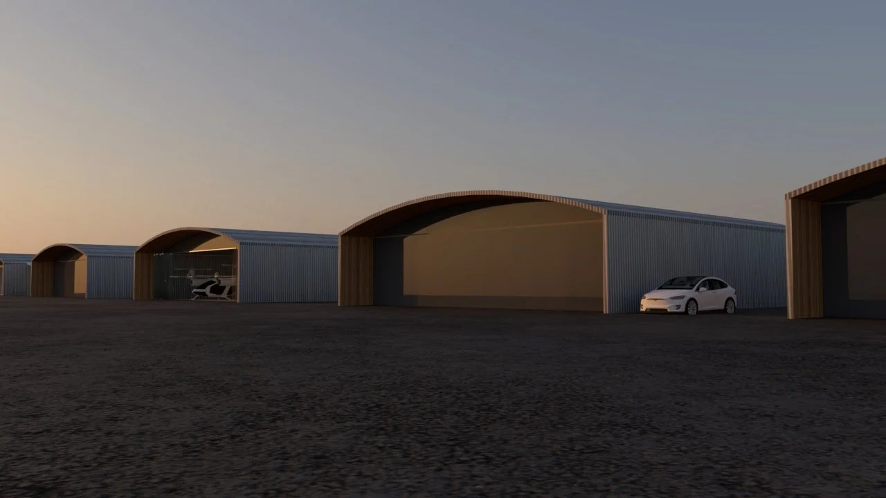 Series of modern hangars with curved roofs, some with open doors showing a helicopter inside and a white car parked outside, set on a flat dirt surface during sunset.