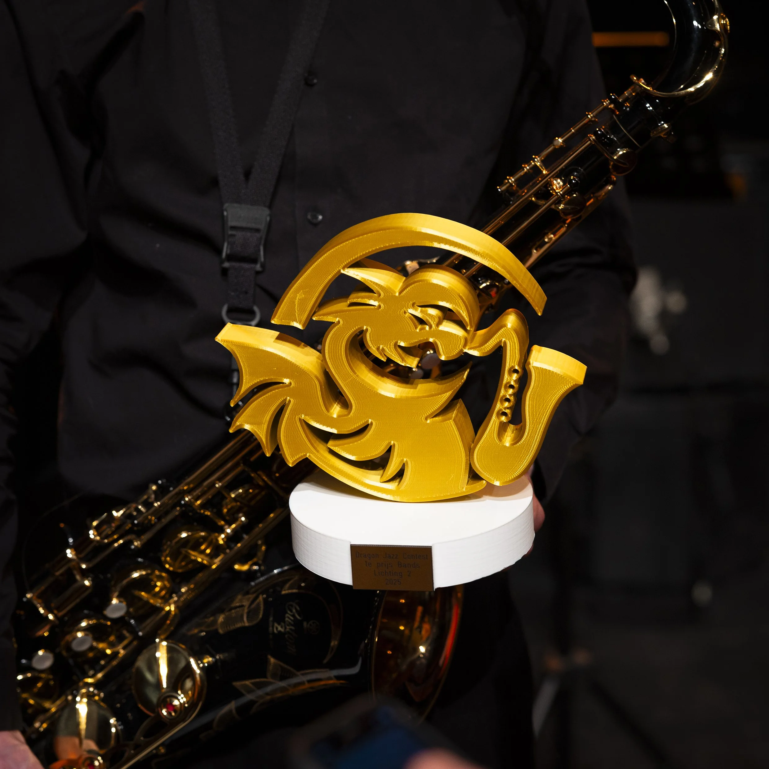 Een close-up van een gouden saxofoon en een prijsbordje dat zegt 'Dragon Jazz Contest 1e prijs Bands Lichten 2 2025'.