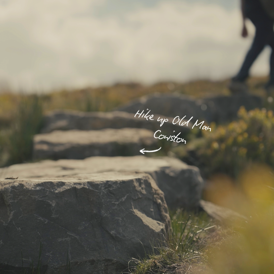 Stone steps leading up a hill, with handwritten text pointing to the first step that says 'Hike up Old Man Coniston' and an arrow indicating the direction.