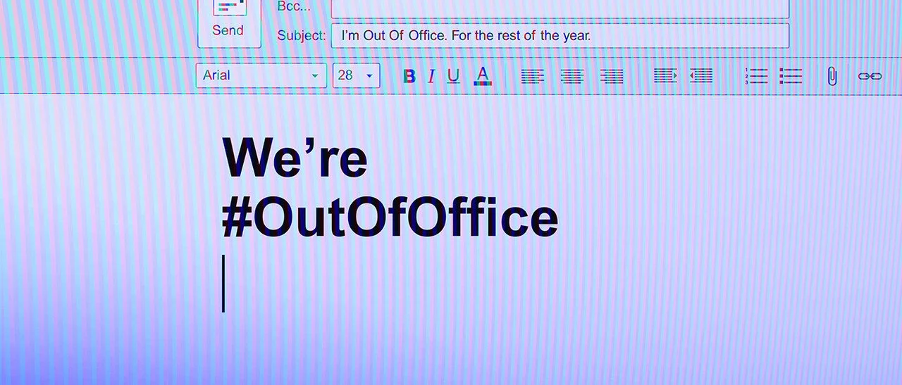 A computer screen displaying an email draft with large bold text that reads "We're #OutOfOffice." The email software interface, with formatting options and email fields, is visible at the top. Campaign created by Katy Stanage