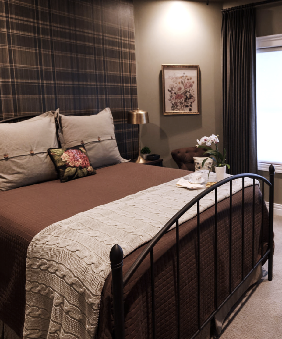 Sage green bedroom with plaid wallpaper. Custom drapery and bedding. Chocolate brown coverlet. Iron Bed frame. Brass lamps. Featherstone Interior Design.