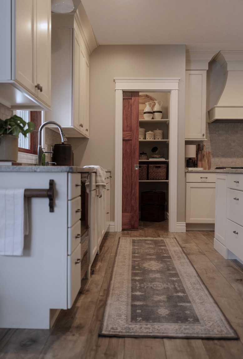 Ivory transitional kitchen with pocket door for pantry. Vintage style runner in front of sink. Featherstone Interior Design. Pulled Together Homes without the Luxury Price Tag.