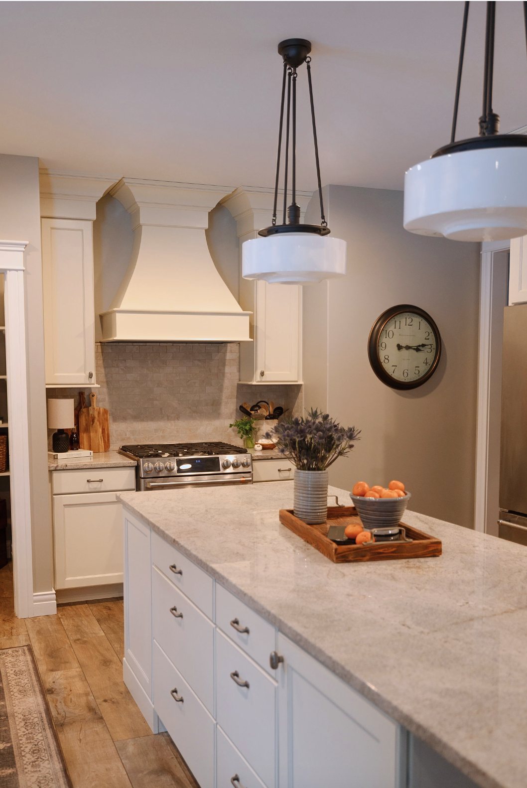 Transitional kitchen with island. Light counters with ivory cabinetry. Large Island. Traditional vent hood over gas range. Featherstone Interior Design.
