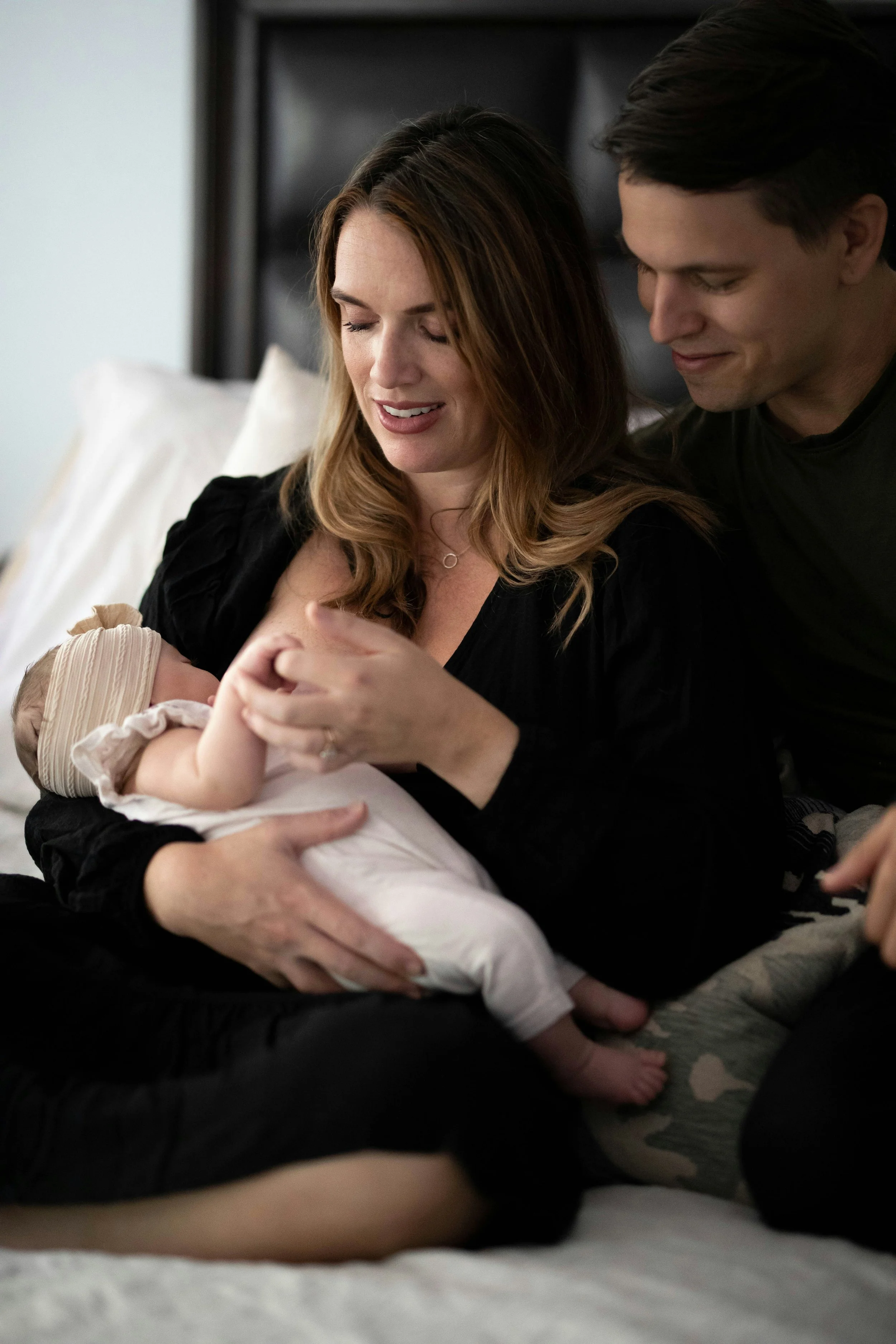 Parents holding newborn baby during early postpartum bonding moment.