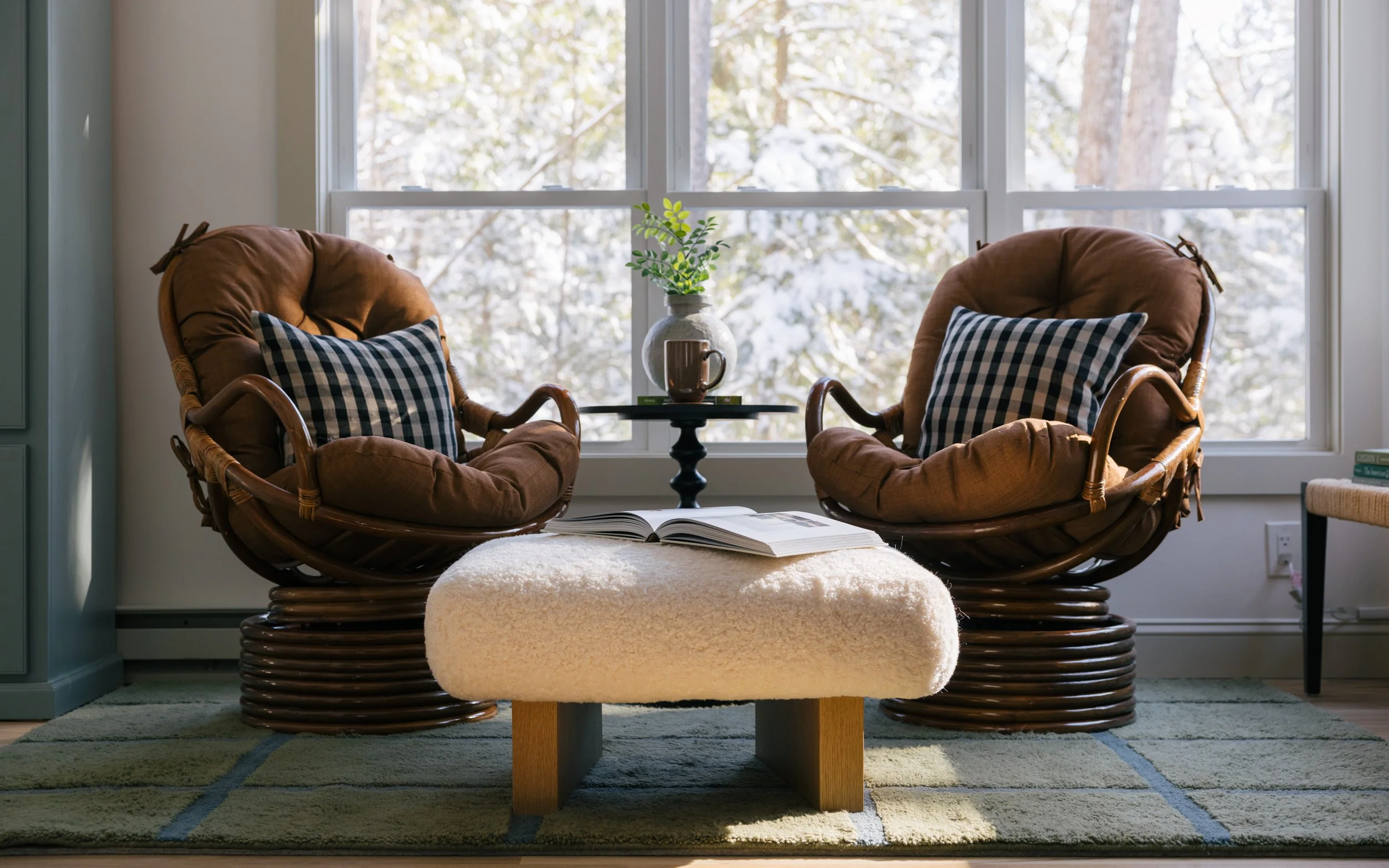 Cozy sitting area at Pine & Plaid in Quechee, Vermont with rattan chairs and large window overlooking winter scenery.