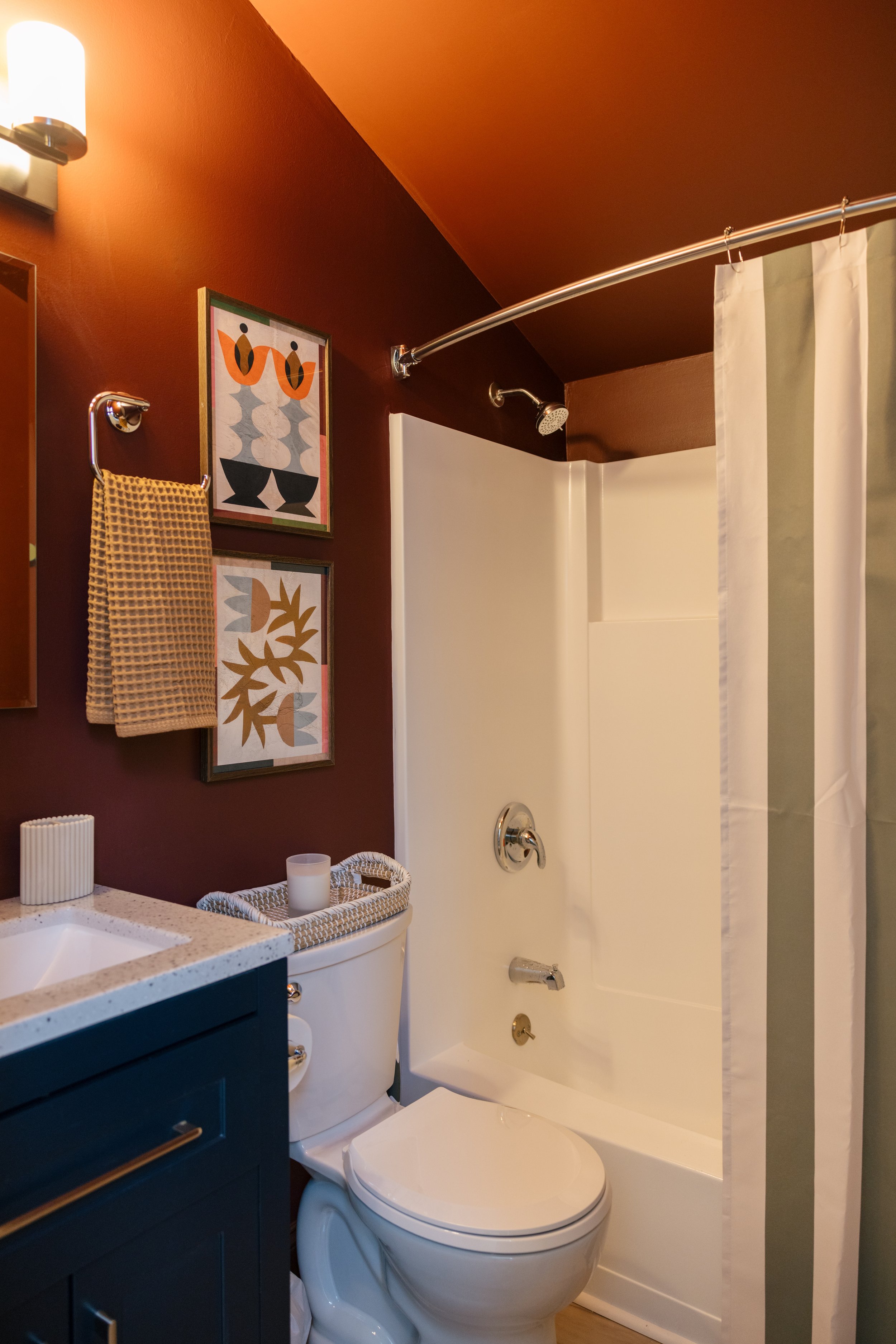 Charming bathroom at Pine & Plaid cabin in Quechee, Vermont with blue vanity, warm accents, and full shower for comfortable family stays.