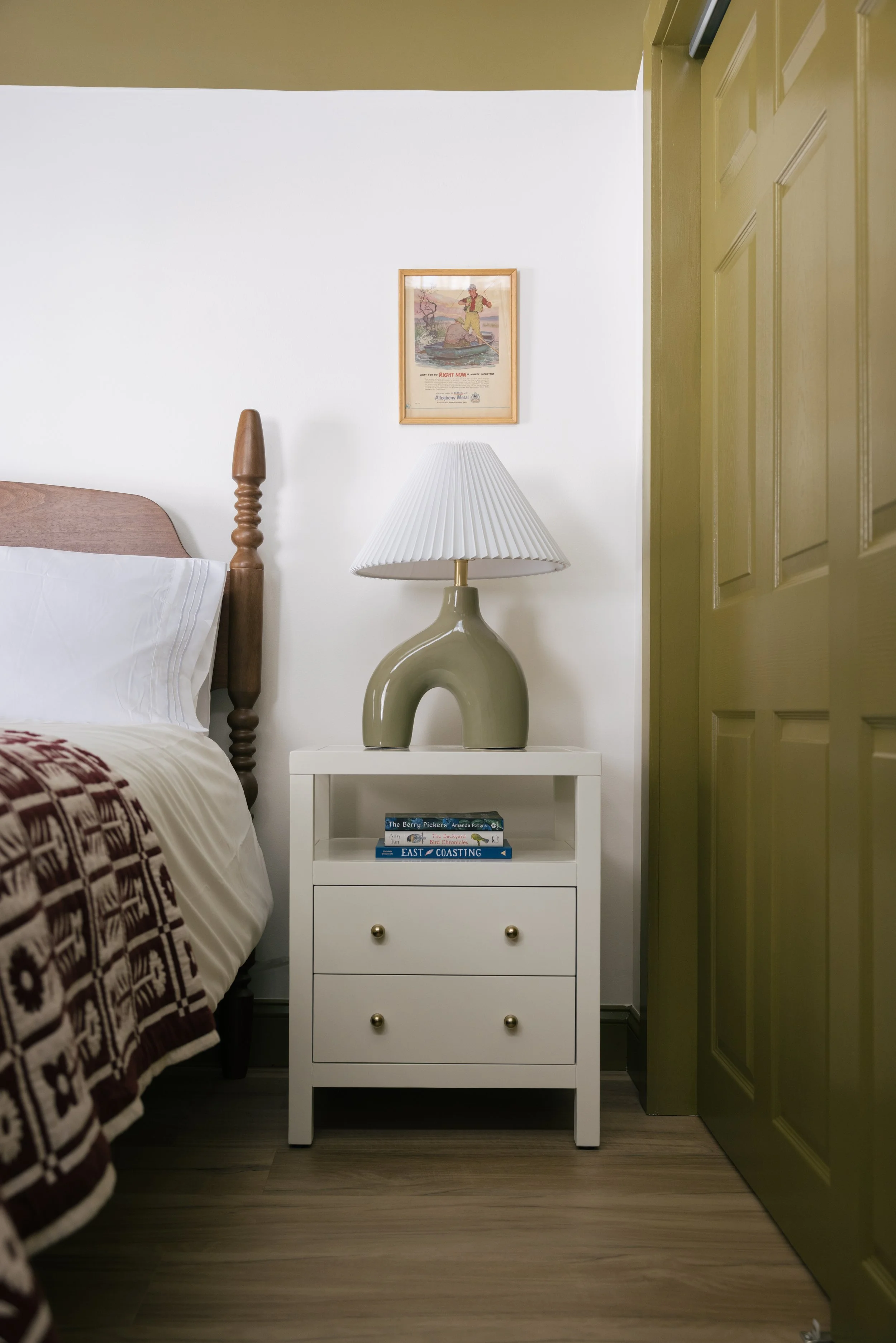 Bedroom detail at Pine & Plaid vacation cabin in Quechee, Vermont with bedside lamp and wooden headboard.