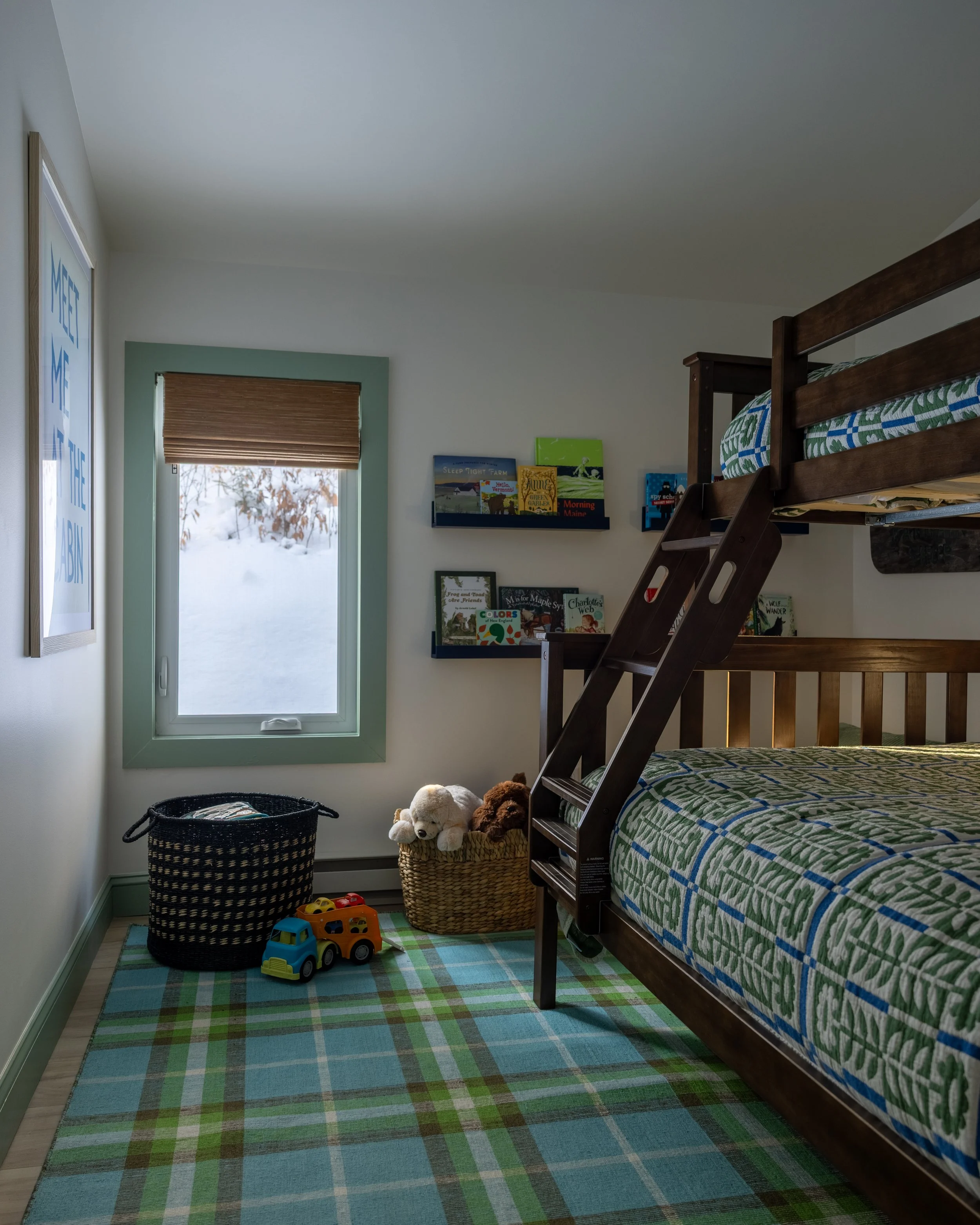 Children’s bunk room at Pine & Plaid Vermont cabin featuring cozy beds, toys, and winter views — perfect for multi-generational family vacations near The Quechee Club.