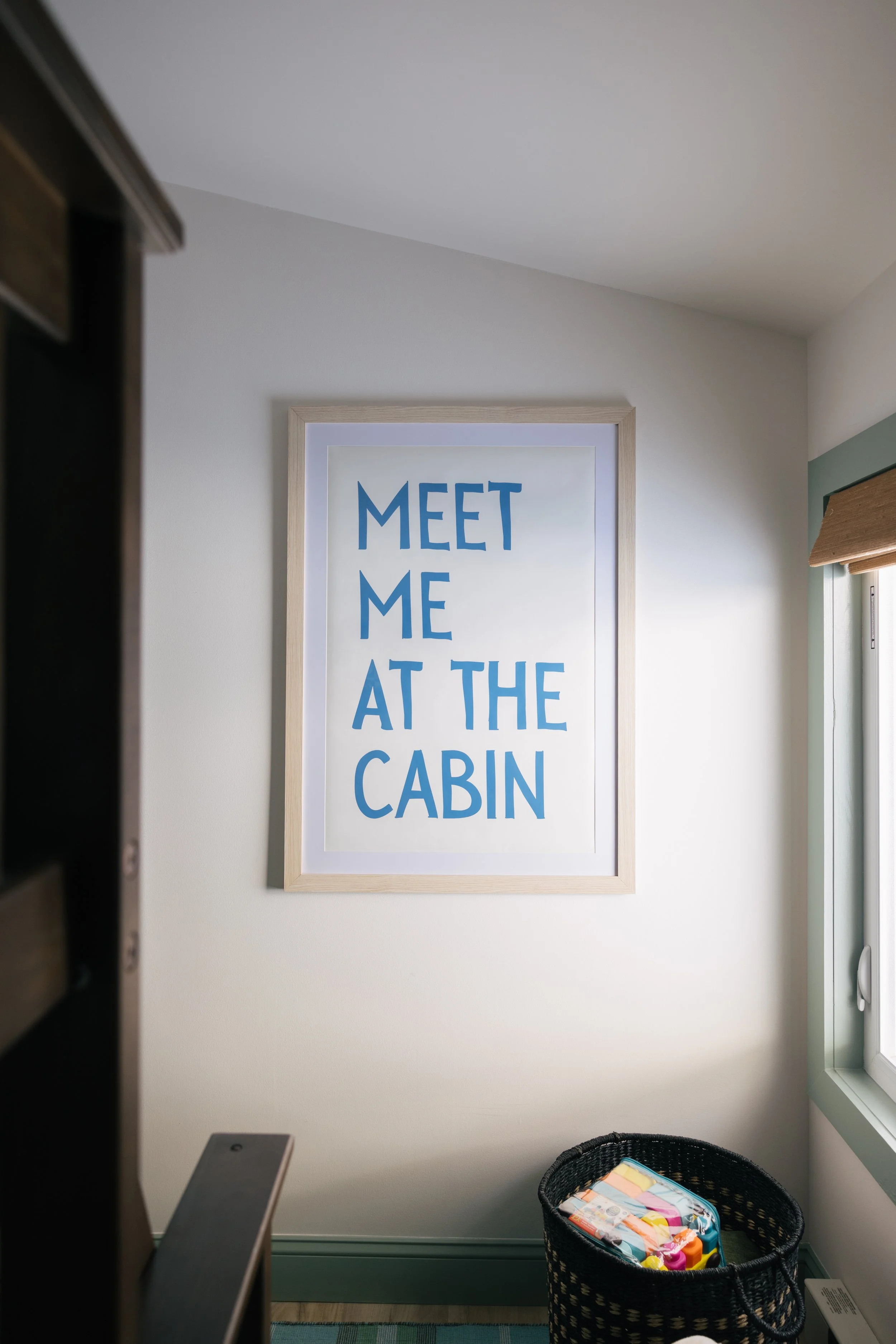 Wall decor at Pine & Plaid cabin rental in Quechee, Vermont featuring “Meet Me at the Cabin” artwork.
