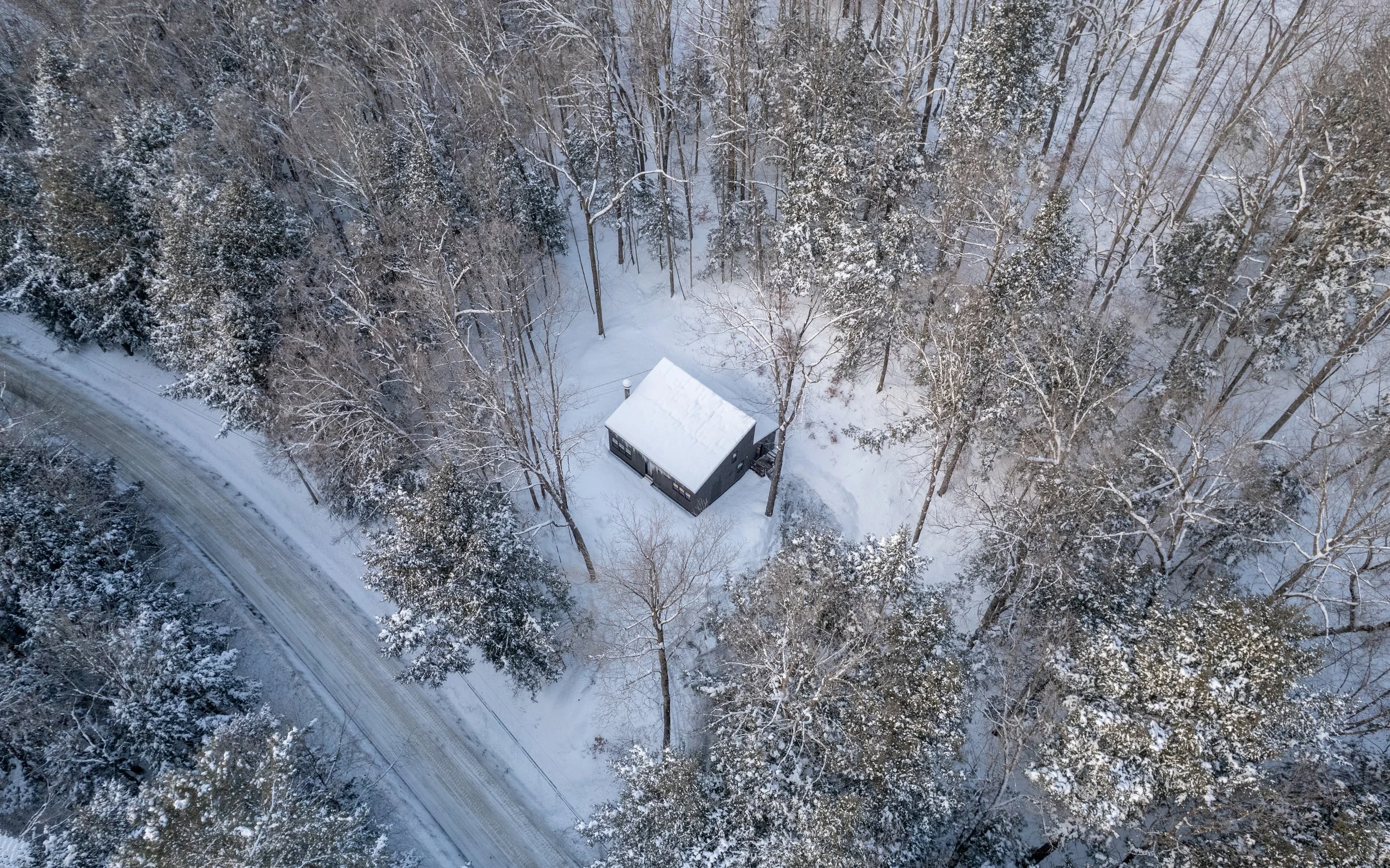 Aerial view of Pine & Plaid cabin rental in Quechee, Vermont surrounded by snowy forest.