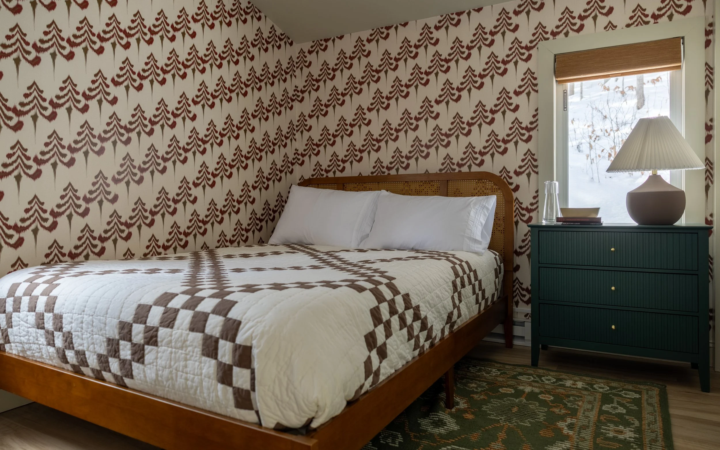 Guest bedroom at Pine & Plaid cabin rental in Quechee, Vermont with wood bed frame and patterned wallpaper.