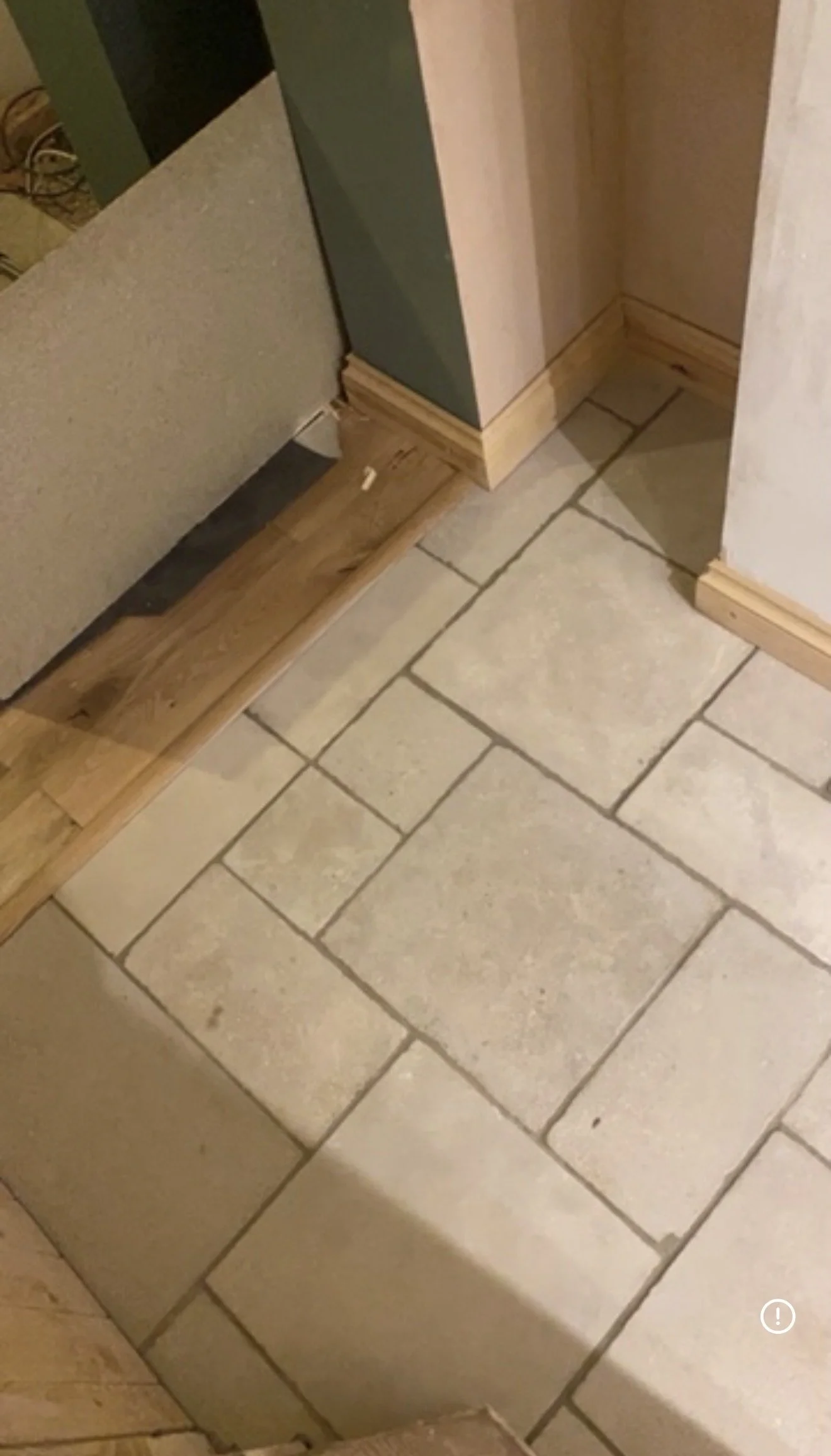 Close-up of finished and unfinished flooring in a room, with a transition between tile and wood, during renovation or construction.
