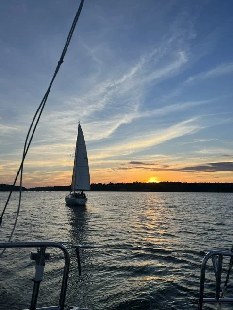 Sailboat on the water during sunset with a clear sky and colorful clouds.