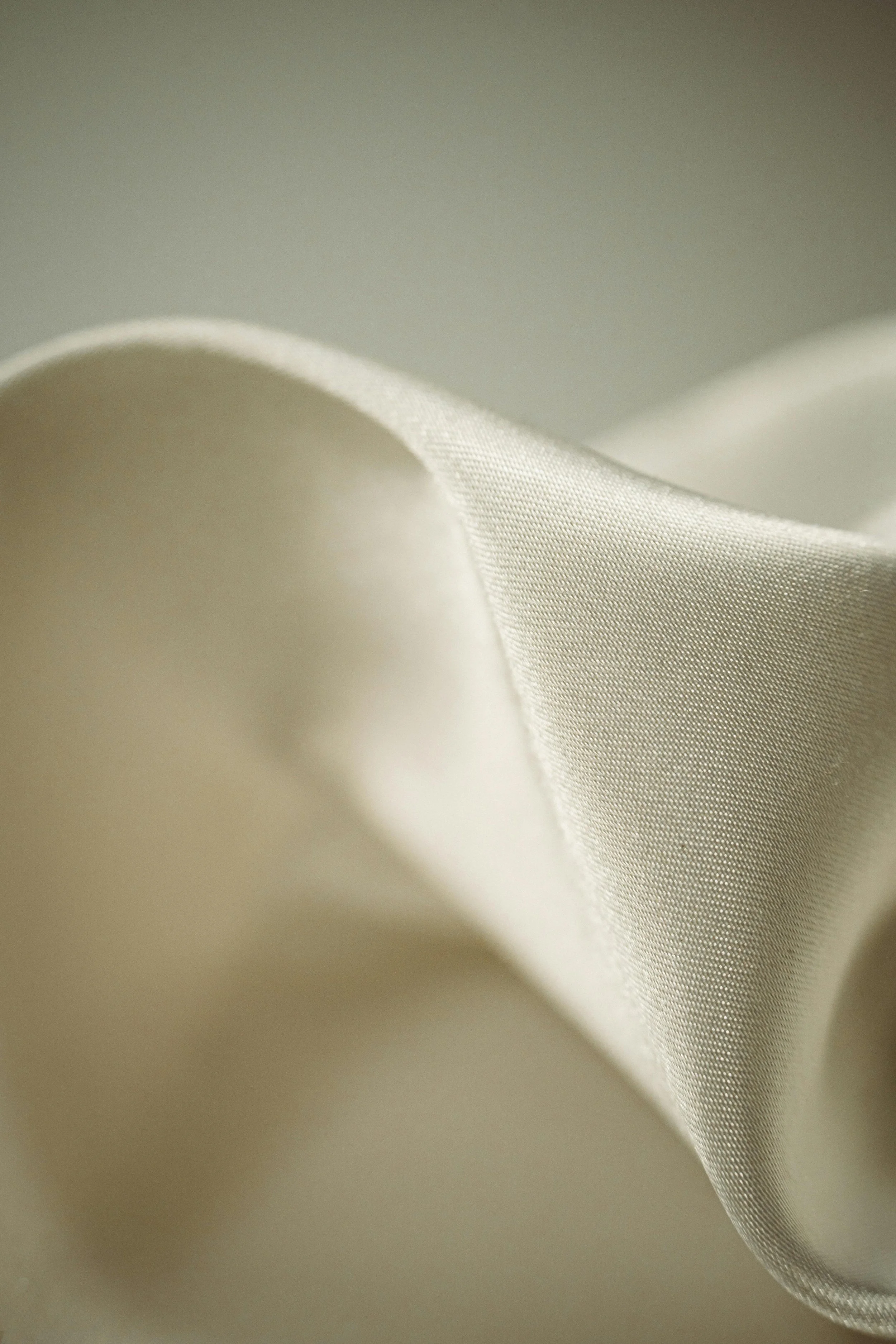 A dress form mannequin with a measuring tape draped around its neck, placed in a room with a plain wall, lit by a spotlight.