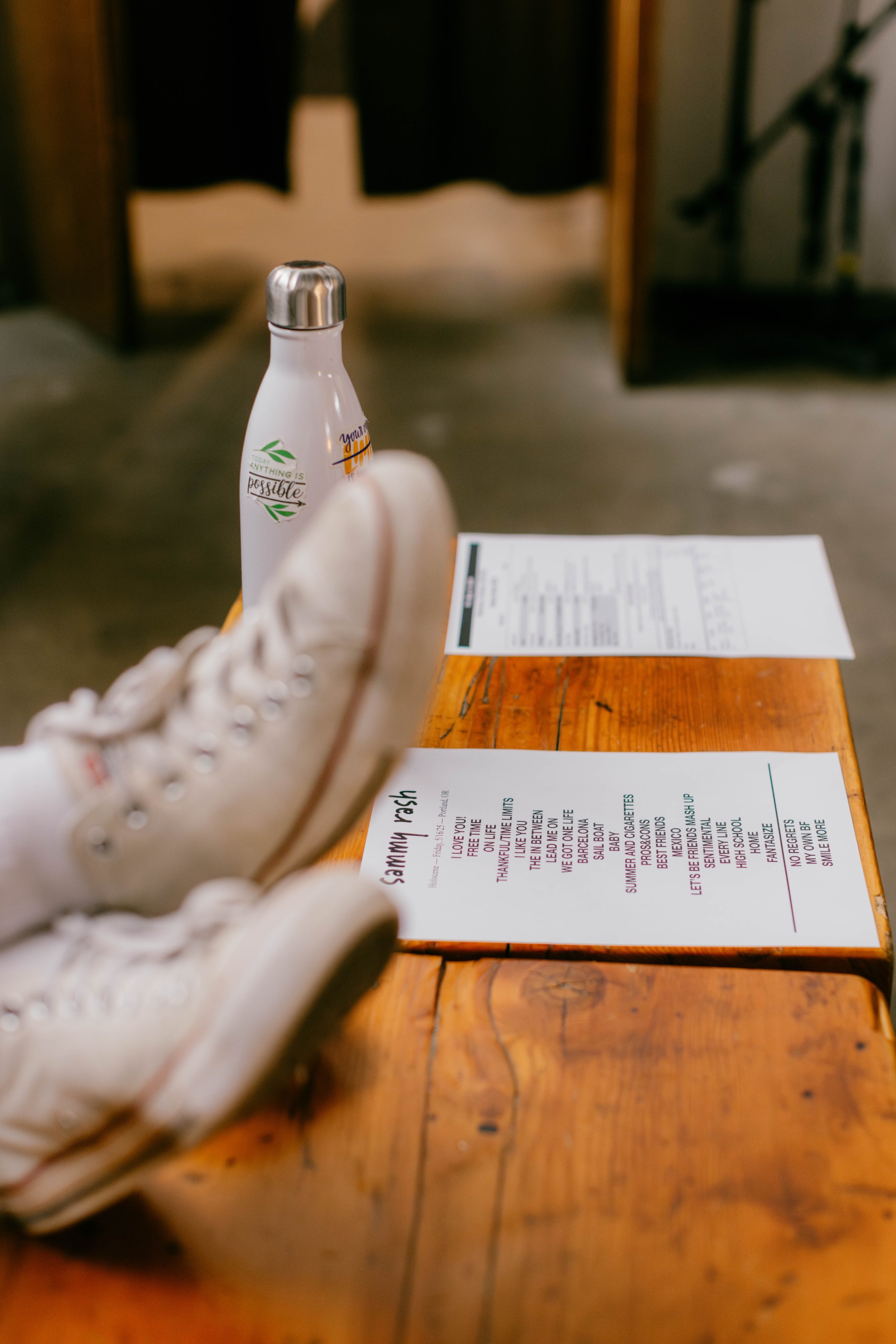 Close-up of a set list before a concert. The person is wearing white sneakers and white socks. 