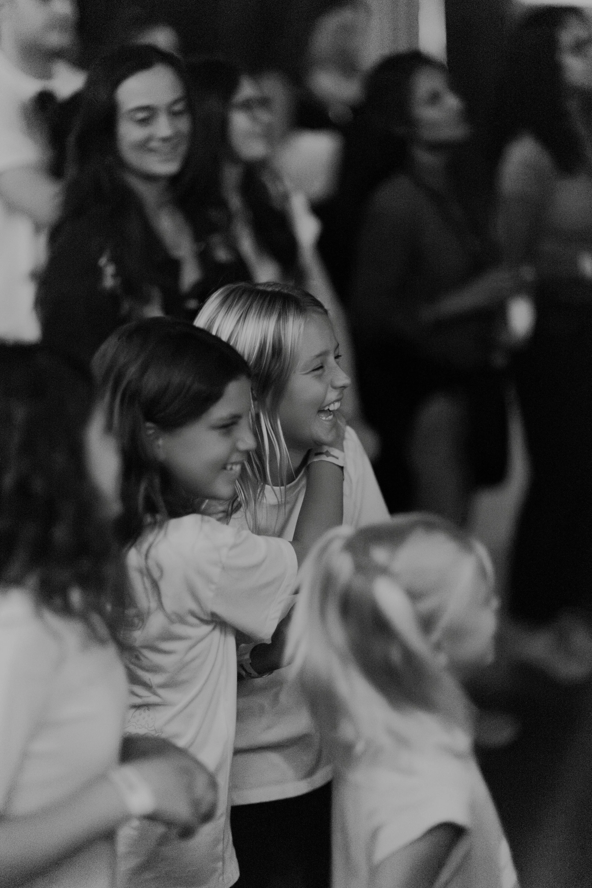 Kids  laughing and smiling at concert, with some standing and others sitting, in a joyful and engaging atmosphere.