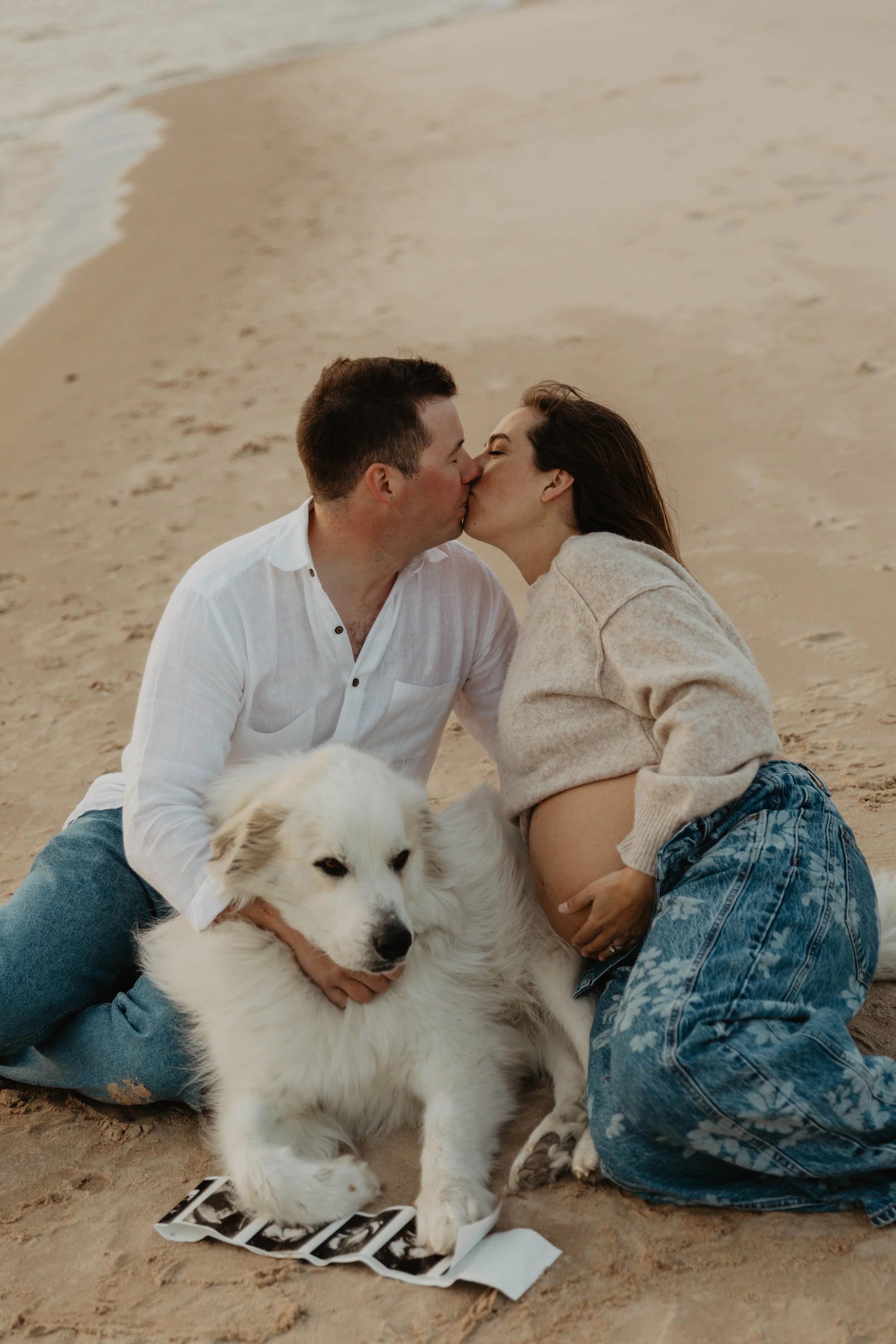 A couple kissing on the beach with their dog and ultrasound images.