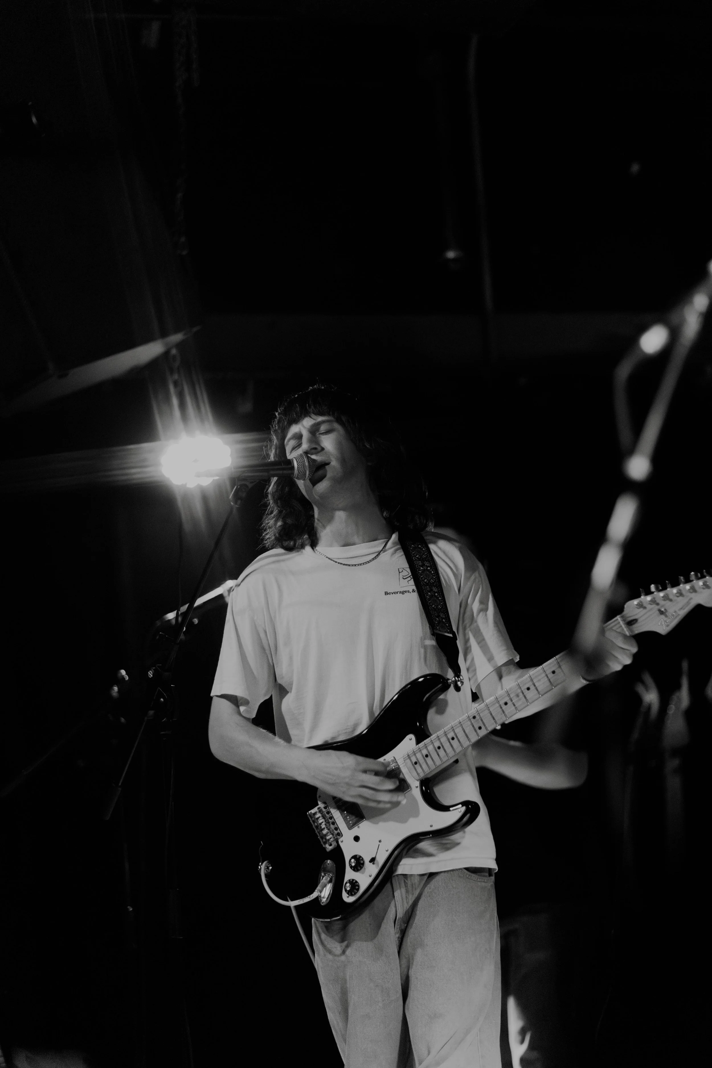 The Band Dipsea Flower singing into a microphone and playing an electric guitar on stage, black and white photo in Chicago.