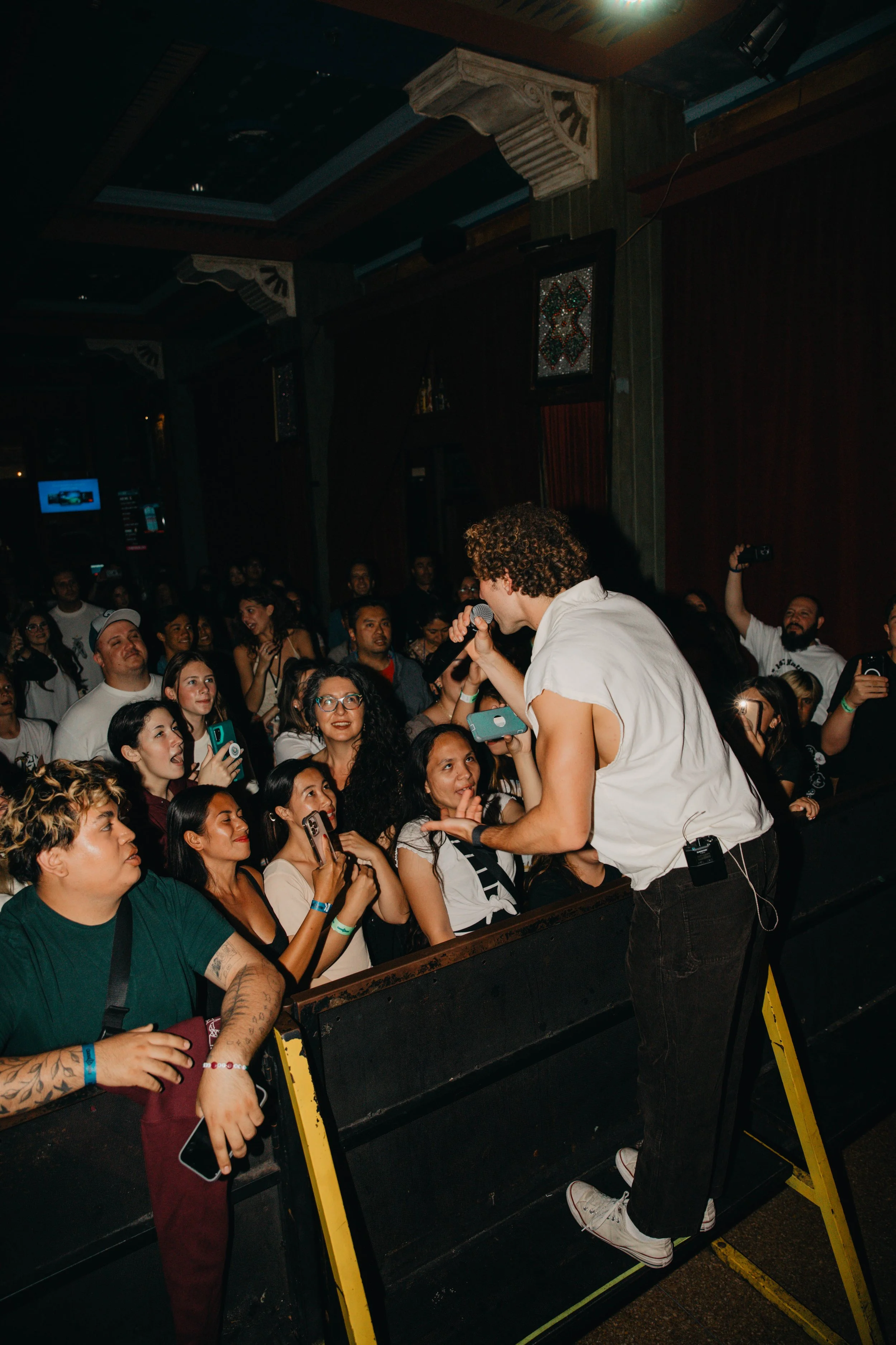 Sammy Rash performing  on stage, engaging with a diverse crowd in a dimly lit venue.