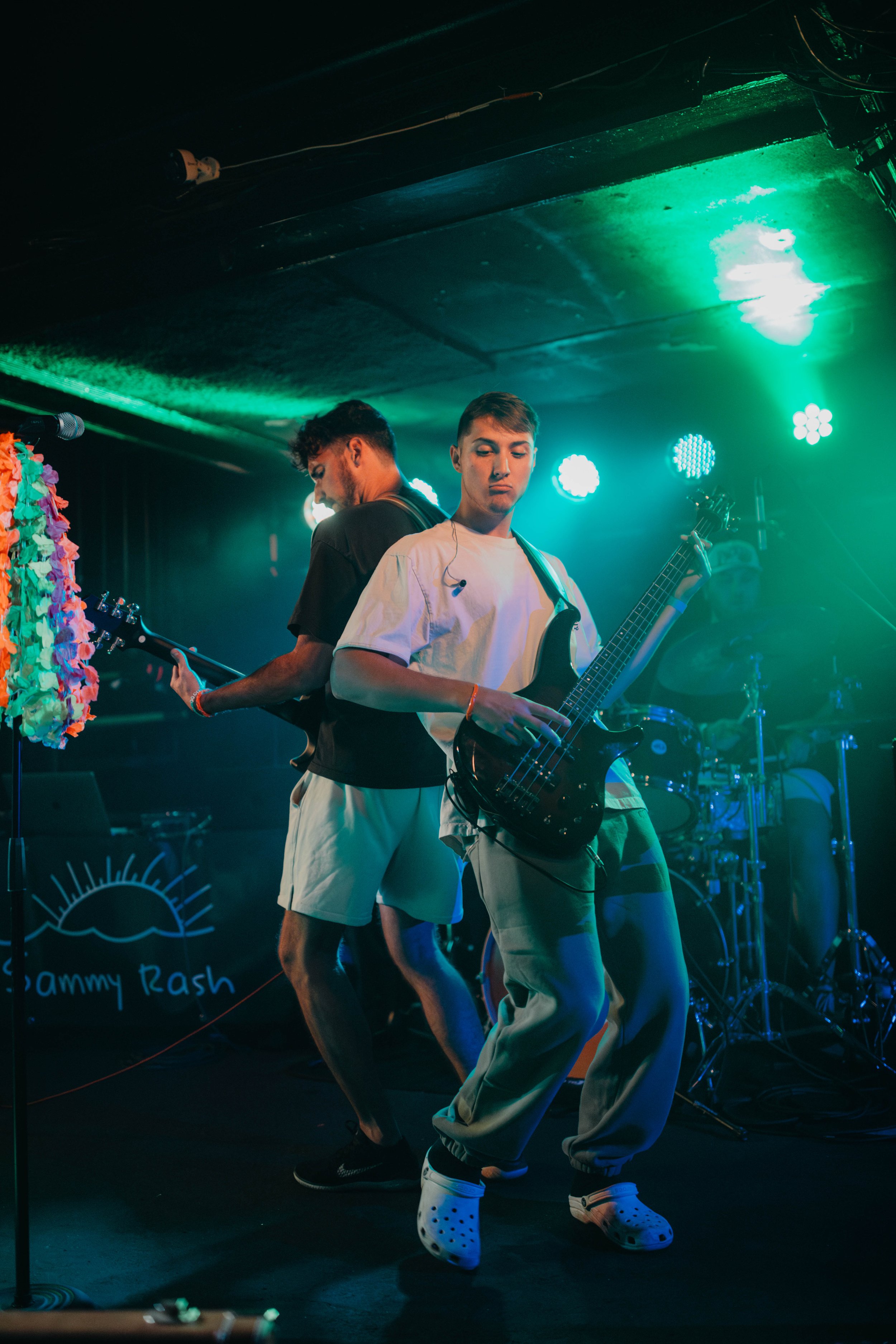 The Astronomers playing guitars and drums on a stage with colorful lighting during a live music performance in Chicago.