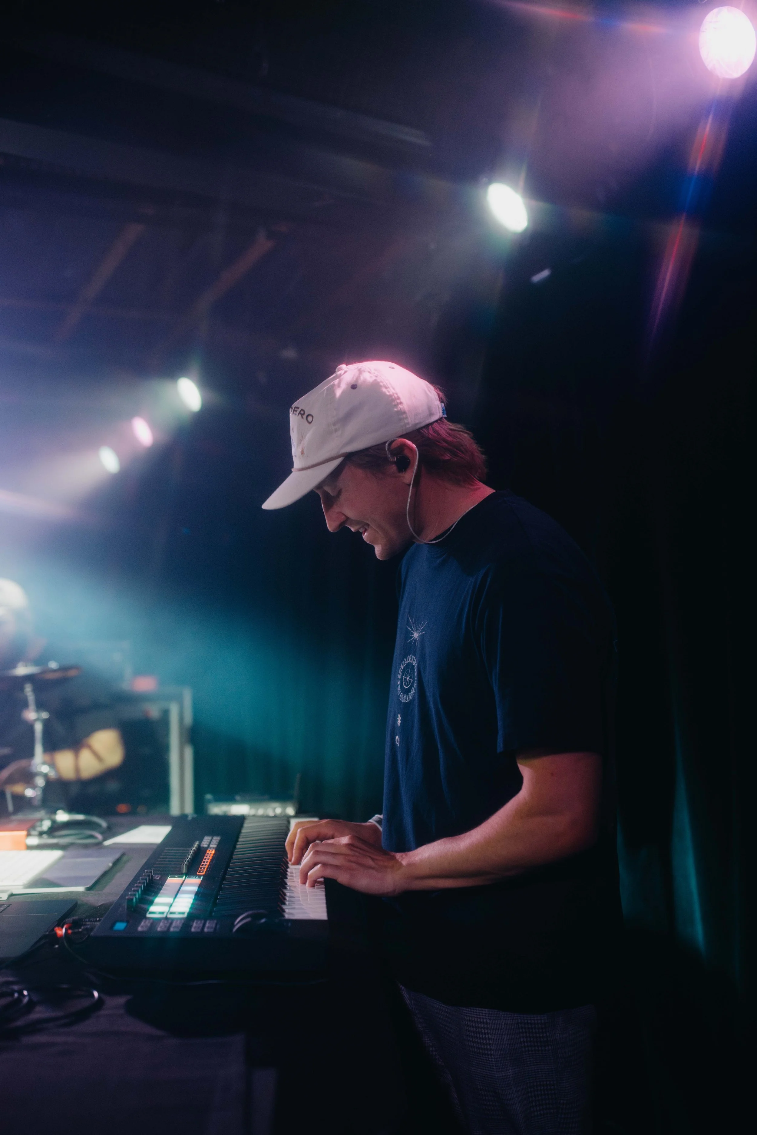 Will, a DJ, performs on stage. He is playing a keyboard on a stage with colorful lights and effects.