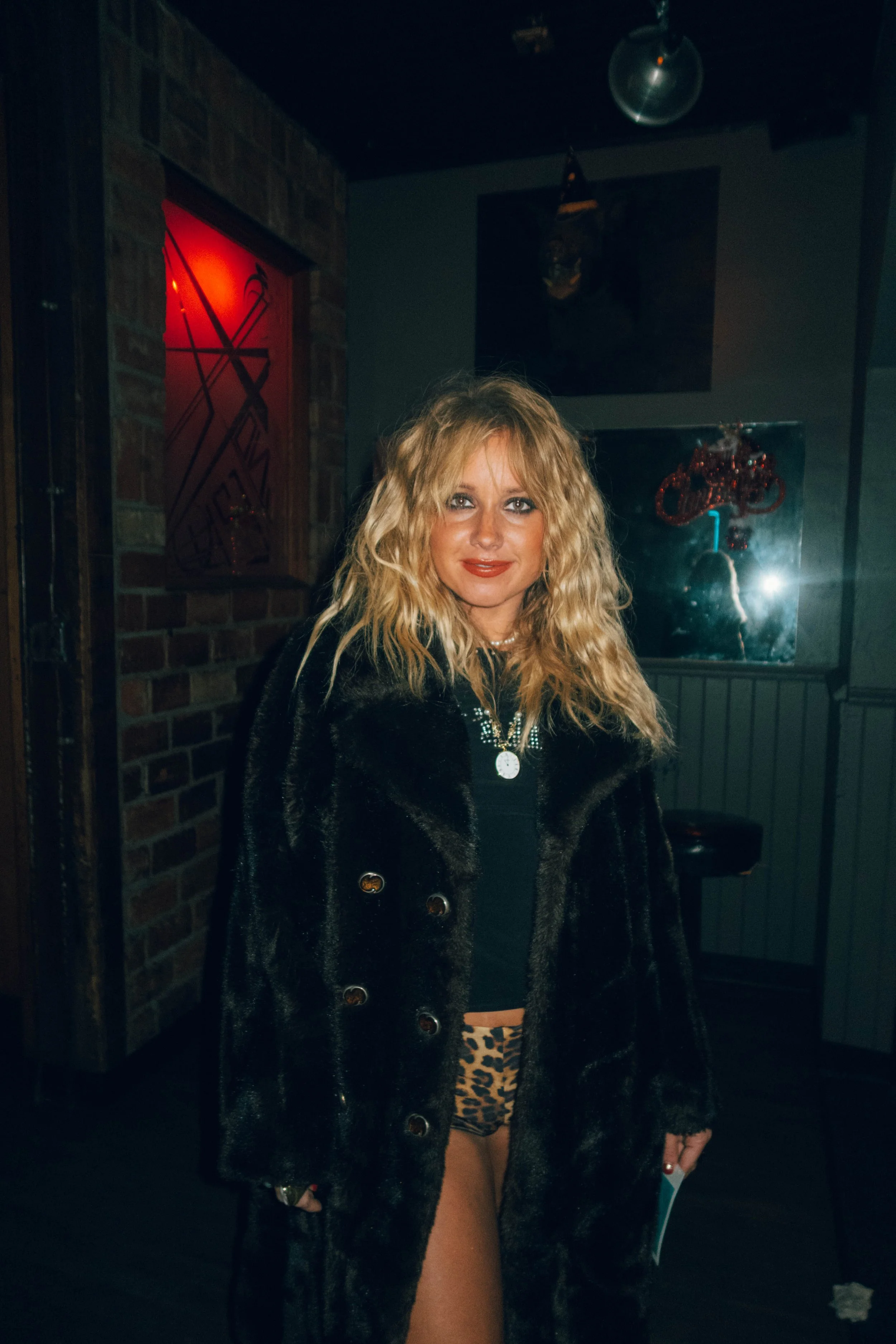 The music artist PEARL, after the concert in Detroit, Michigan. She has curly blonde hair smile wearing a black fur coat and leopard print shorts.