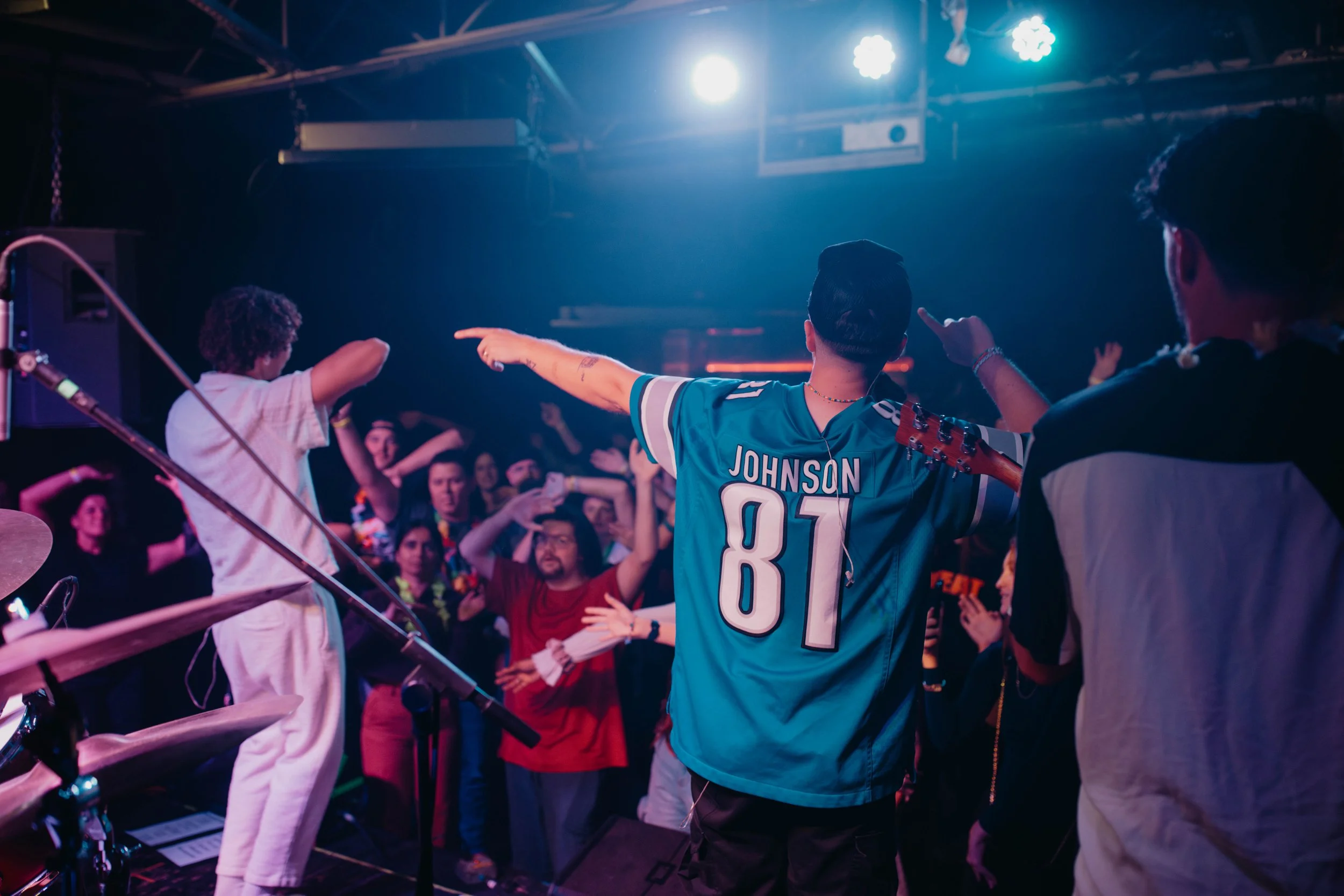 Sammy Rash and The Astronomers performing at a concert in Michigan. The stage is lit with bright lights, and the atmosphere is lively and energetic.