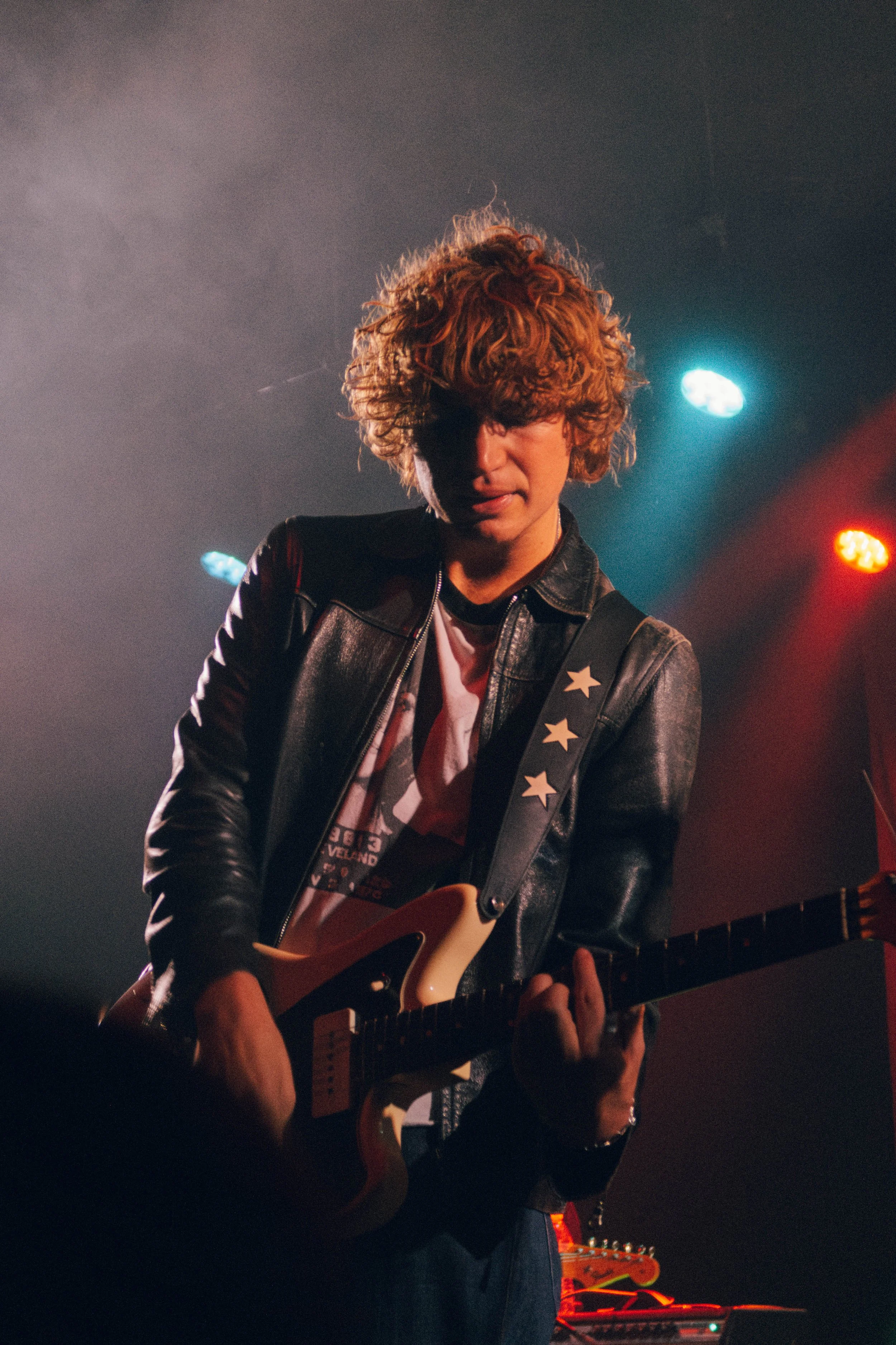The band SUNROOM playing an electric guitar on stage under colorful lights in Chicago.