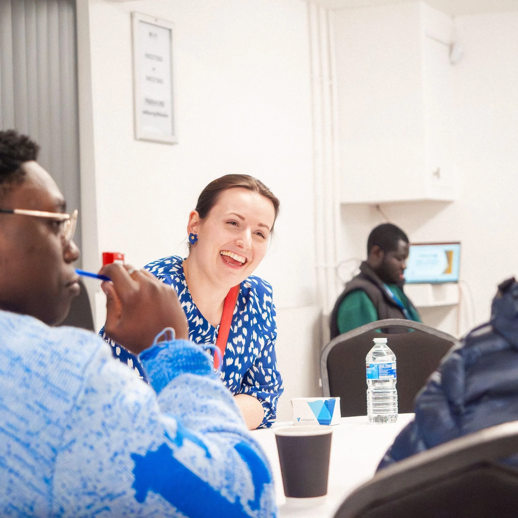 A woman smiling at a table discussion during an event